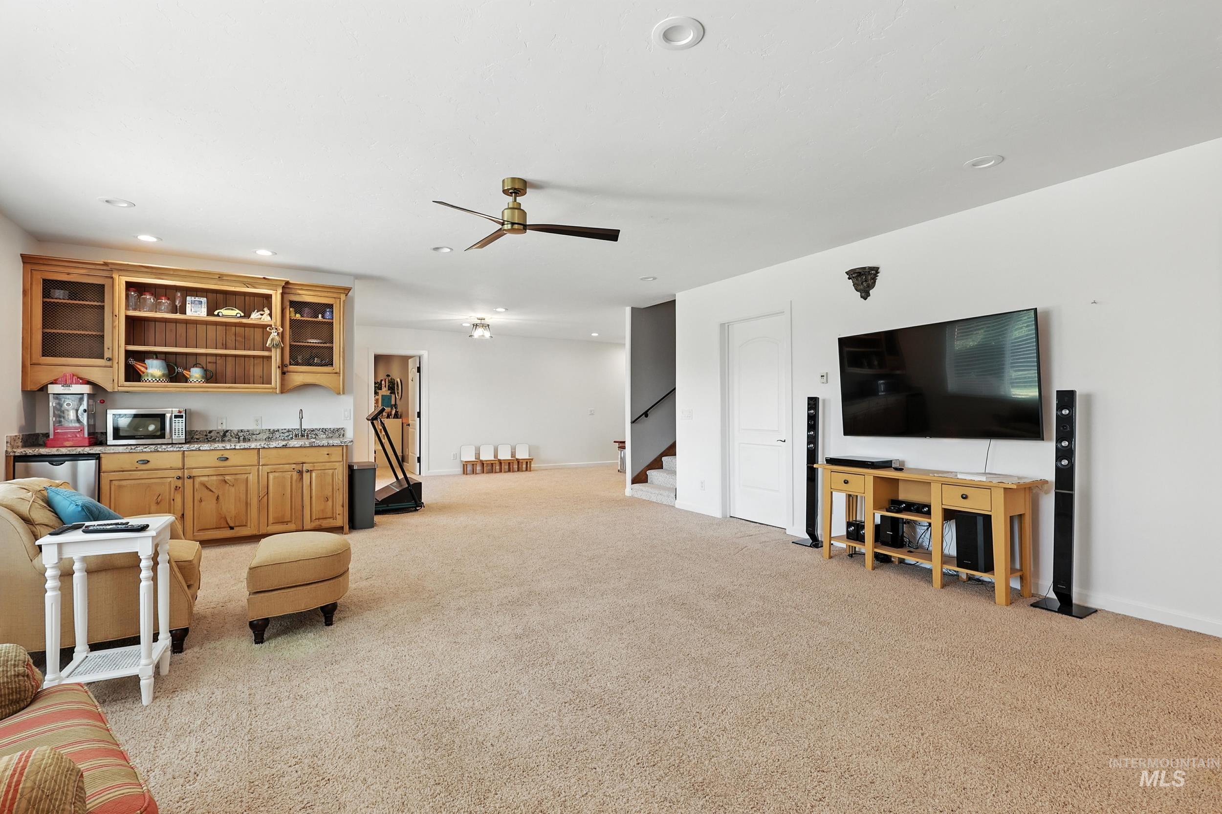 Living room with light carpet, recessed lighting, a ceiling fan, and stairway