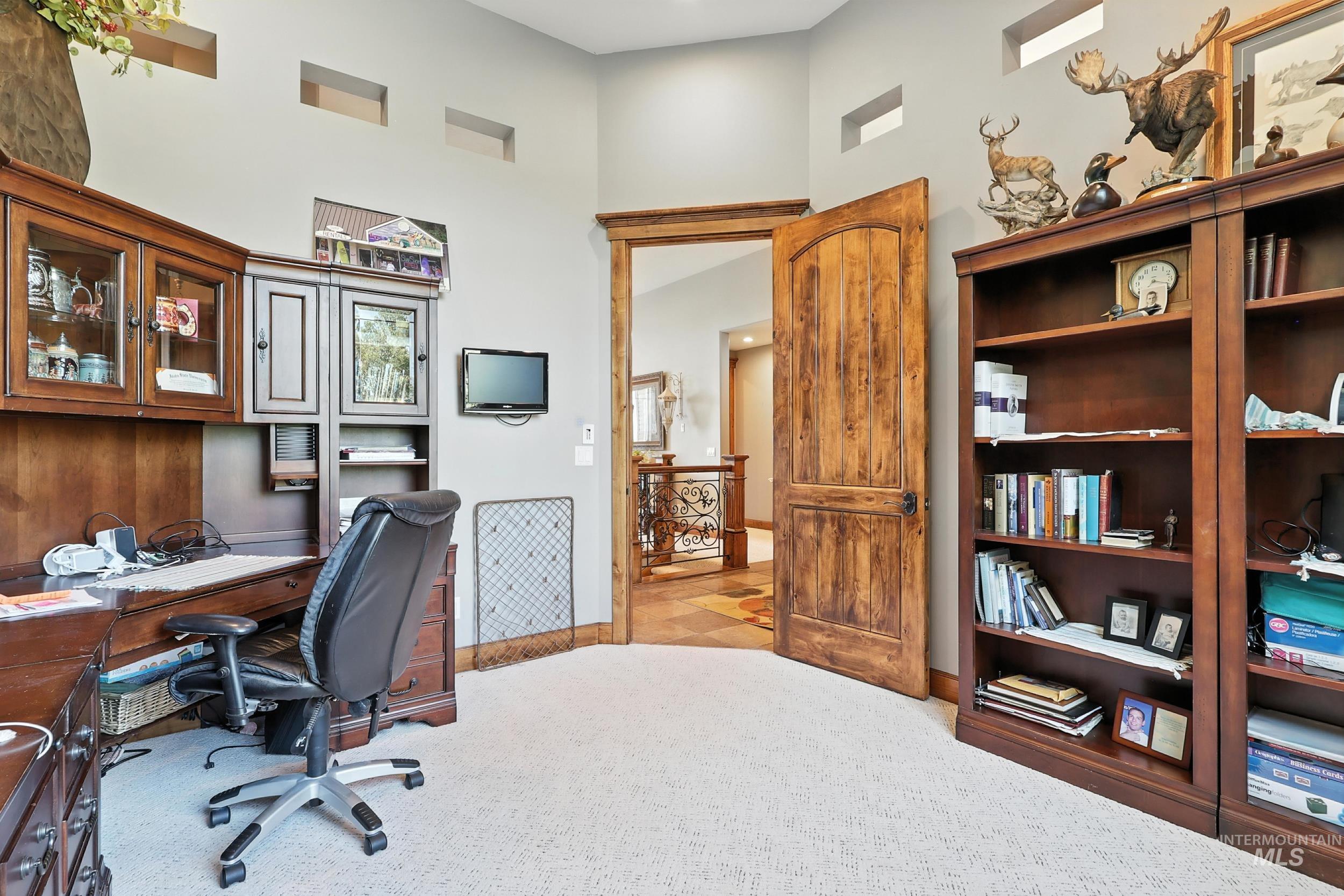 Home office with light colored carpet and a towering ceiling