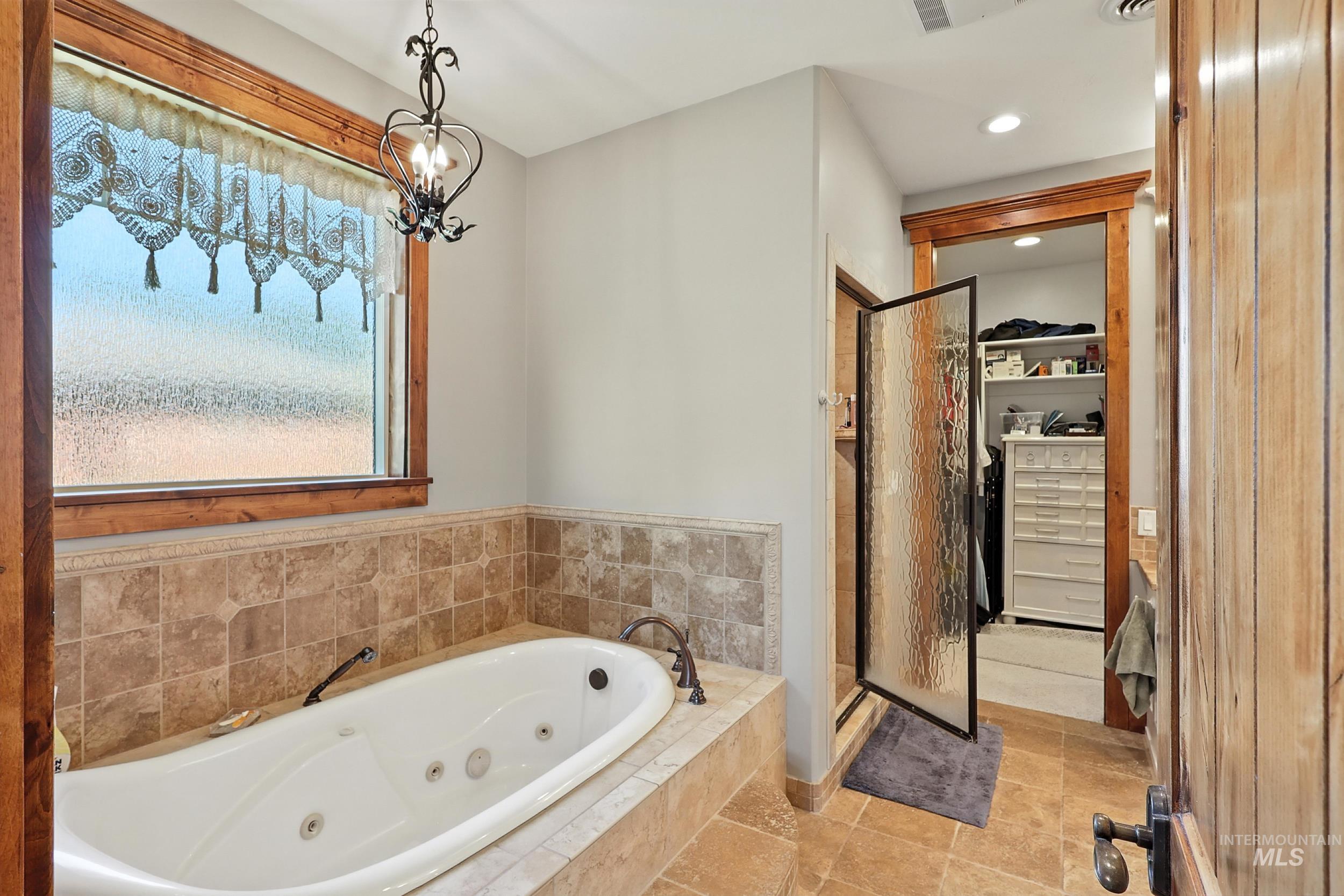 Bathroom featuring a shower stall, a whirlpool tub, a spacious closet, recessed lighting, and a chandelier