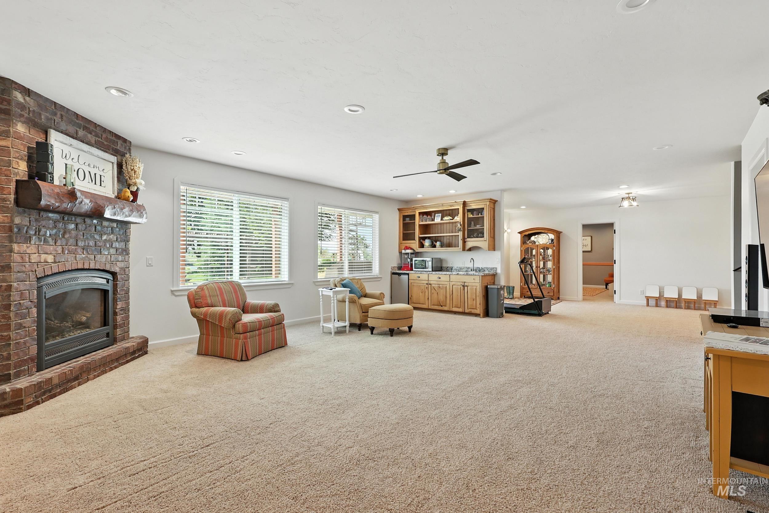 Living area featuring light colored carpet, recessed lighting, a fireplace, and ceiling fan