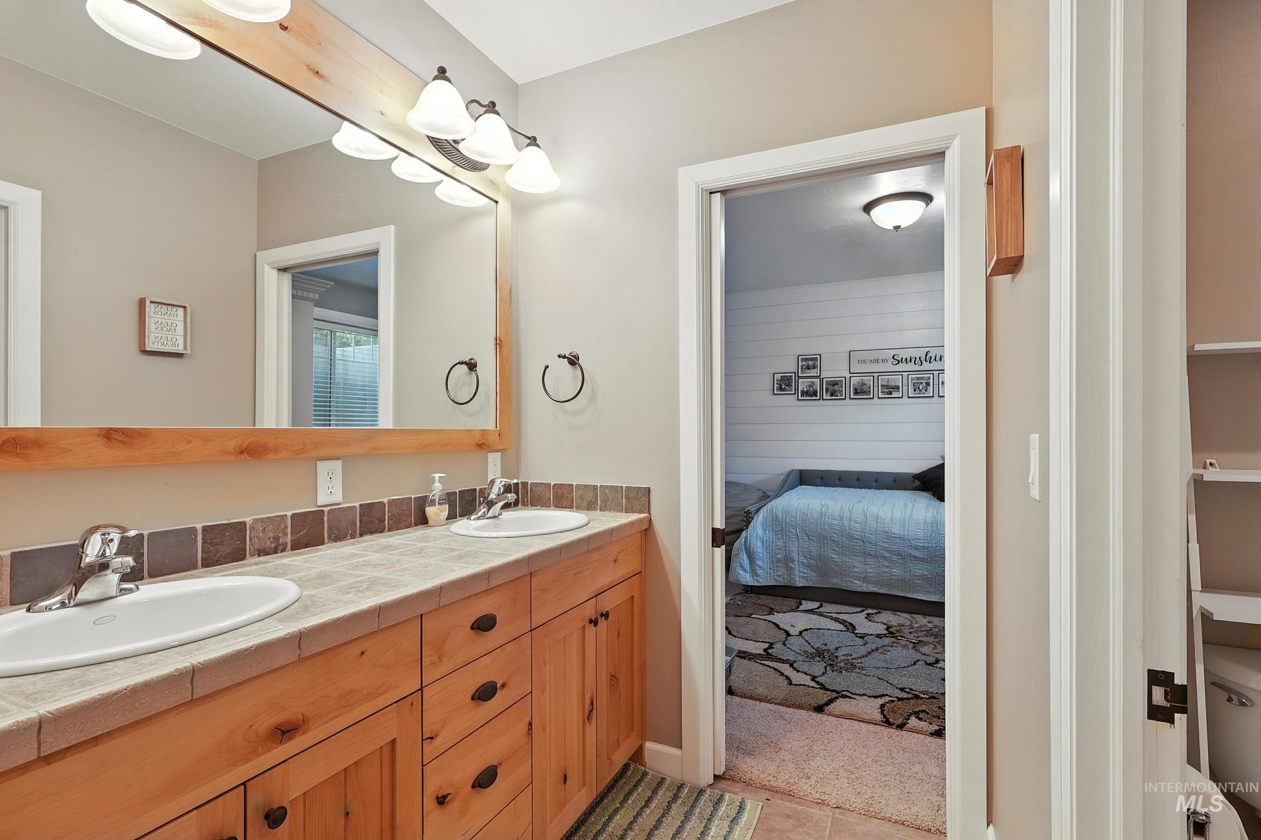 Ensuite bathroom with double vanity and light tile patterned floors