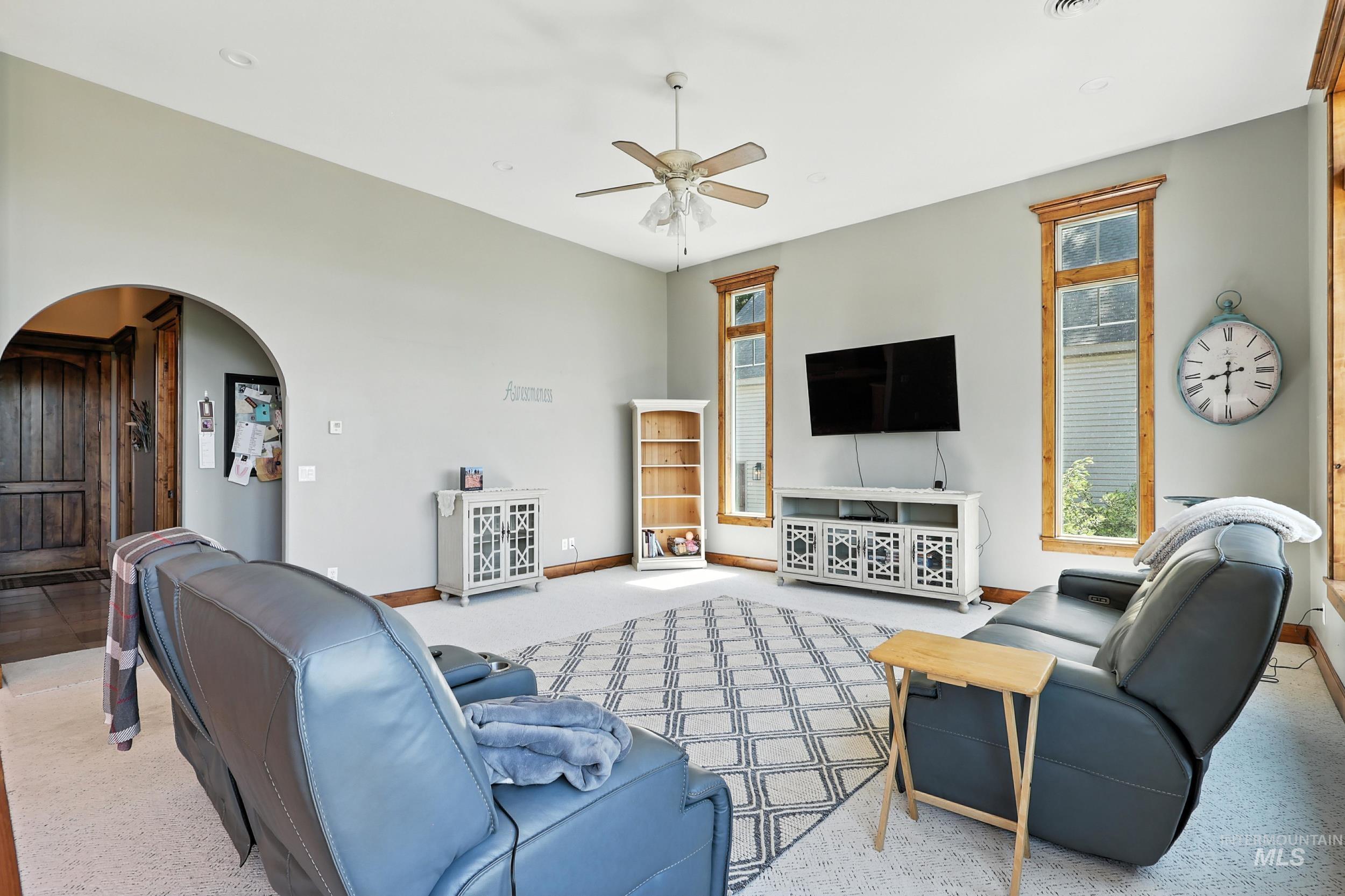 Carpeted living room featuring arched walkways and a ceiling fan