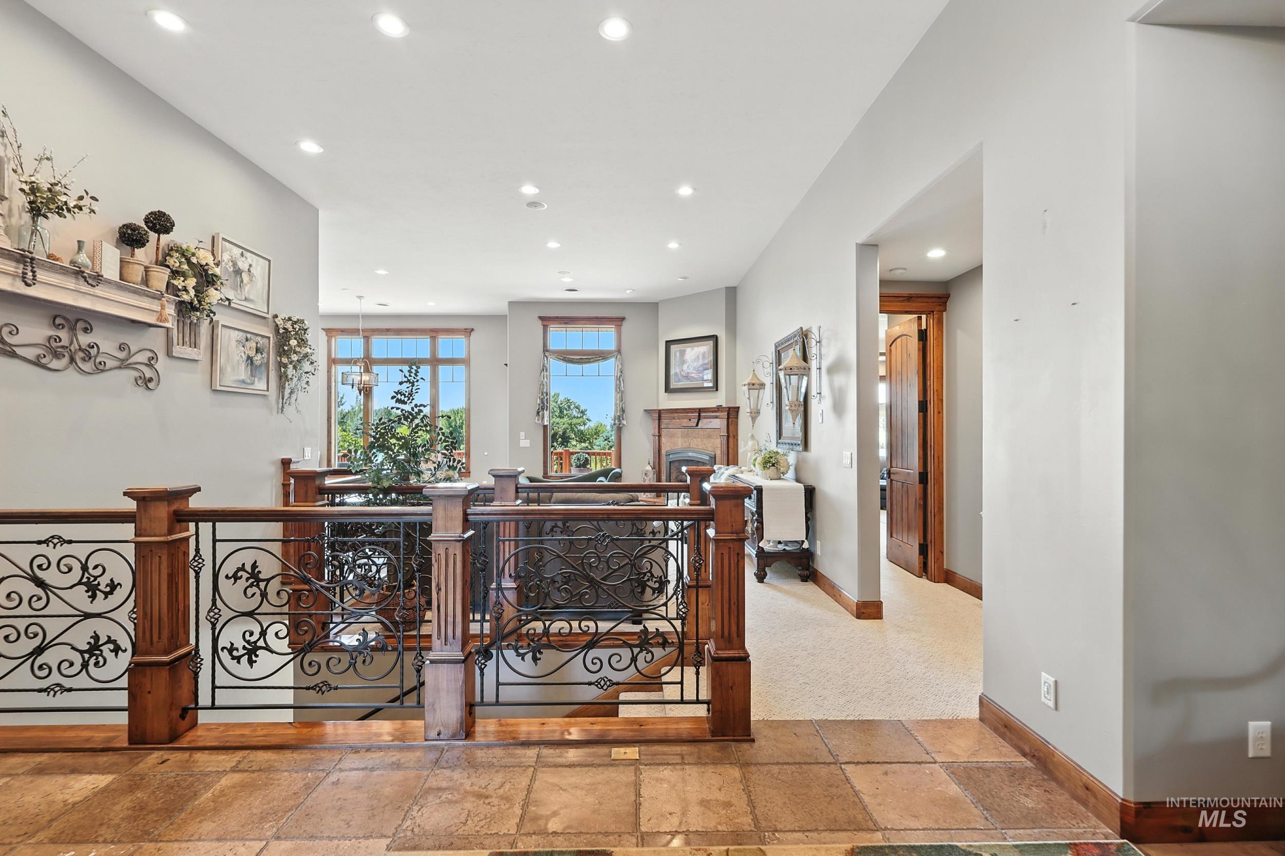 Hallway with stone tile floors, an upstairs landing, and recessed lighting