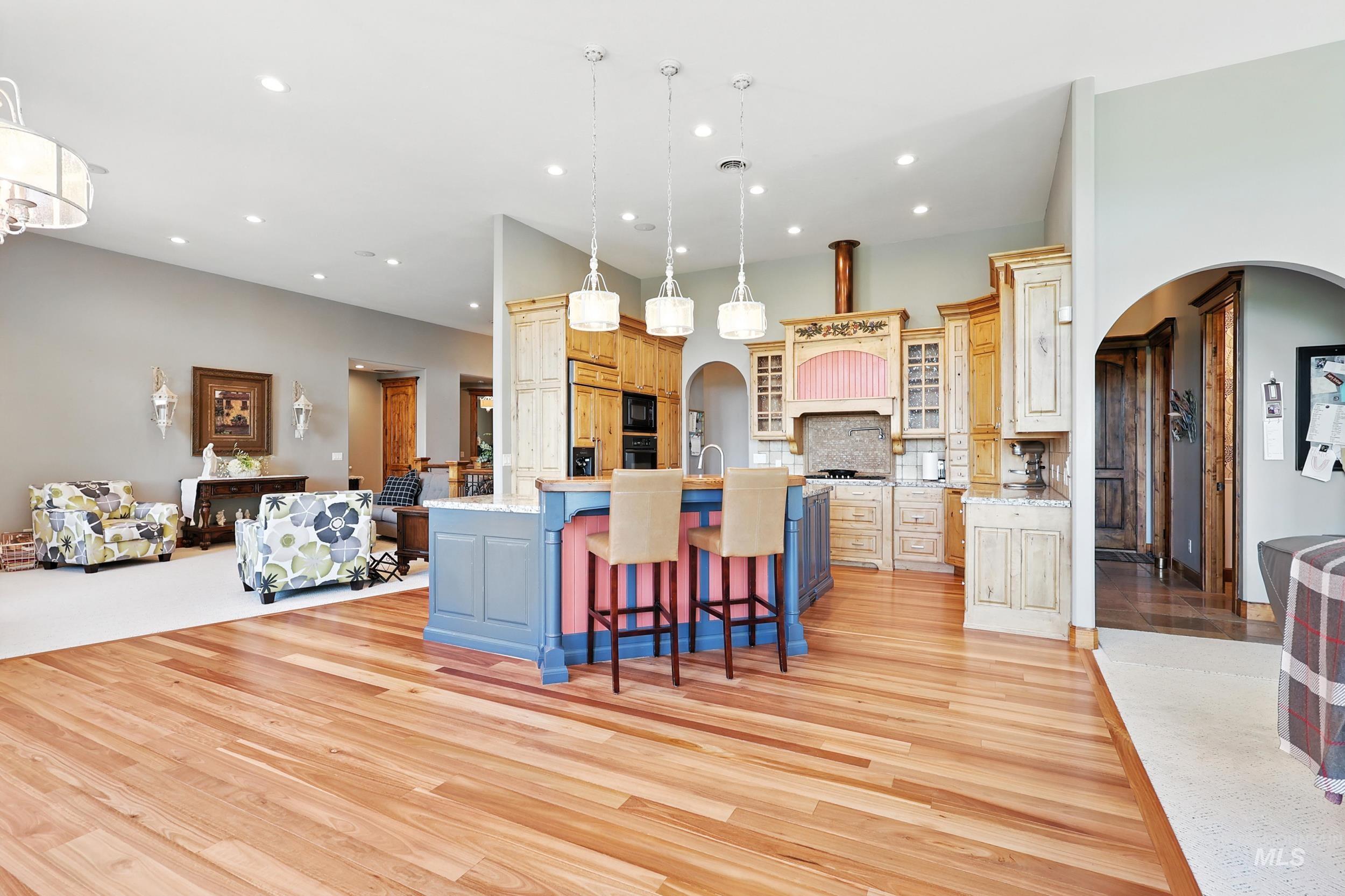 Kitchen featuring arched walkways, a kitchen bar, decorative light fixtures, open floor plan, and recessed lighting