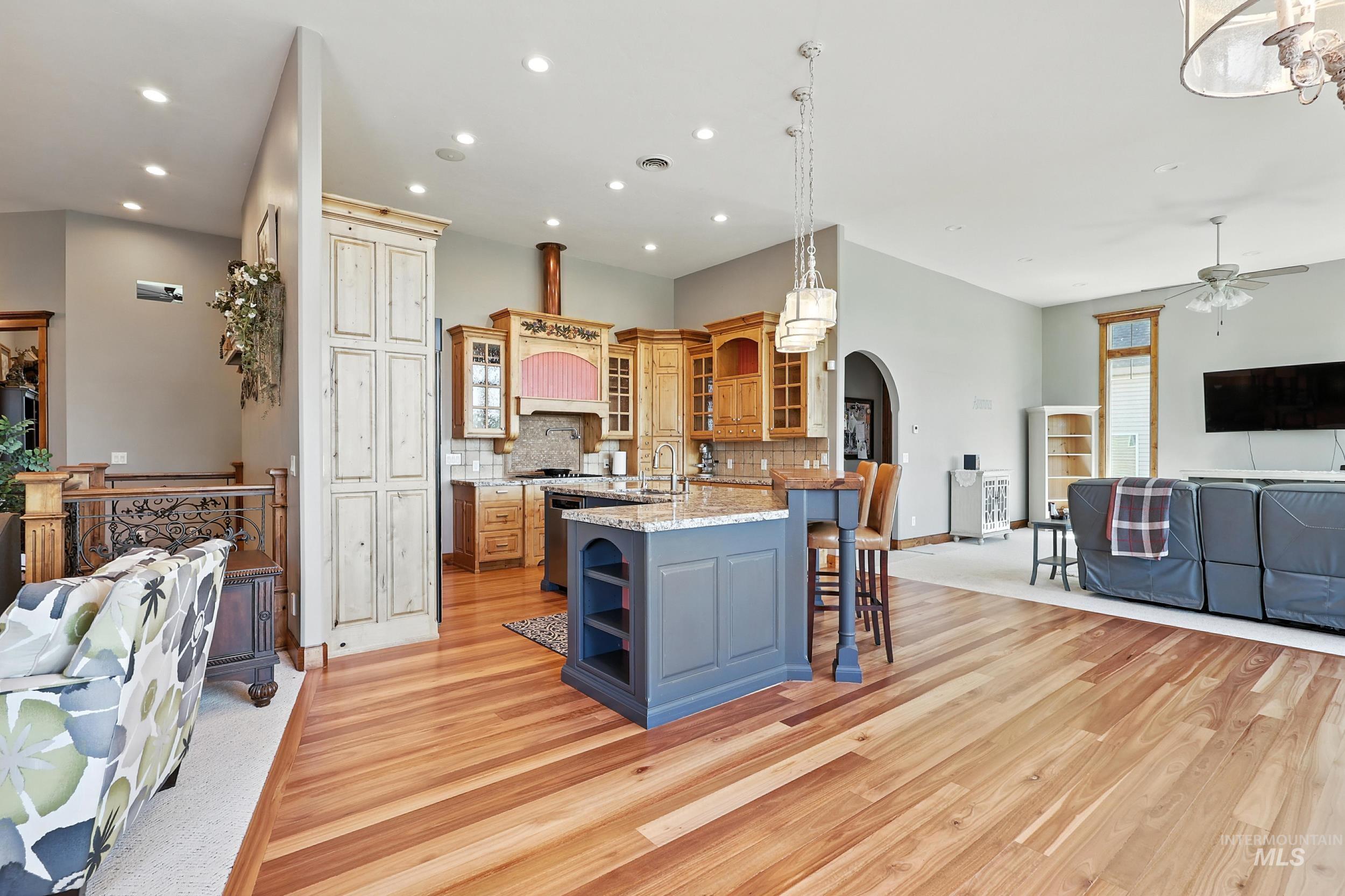 Kitchen featuring open shelves, open floor plan, glass insert cabinets, a kitchen breakfast bar, and decorative backsplash