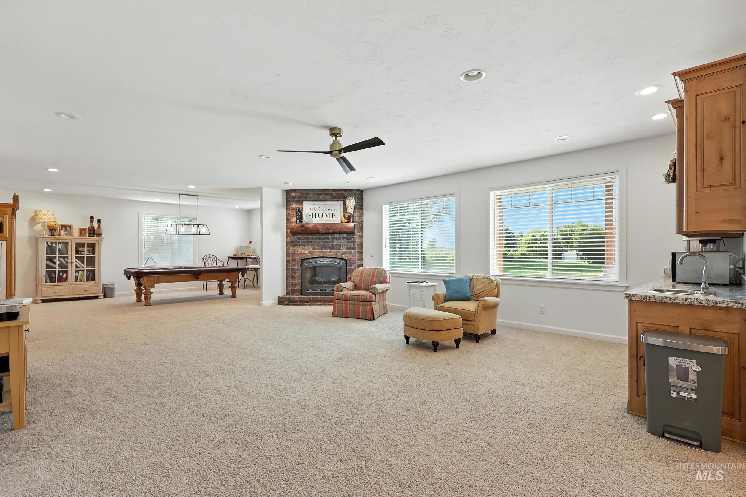 Living room with light carpet, ceiling fan, recessed lighting, a fireplace, and pool table