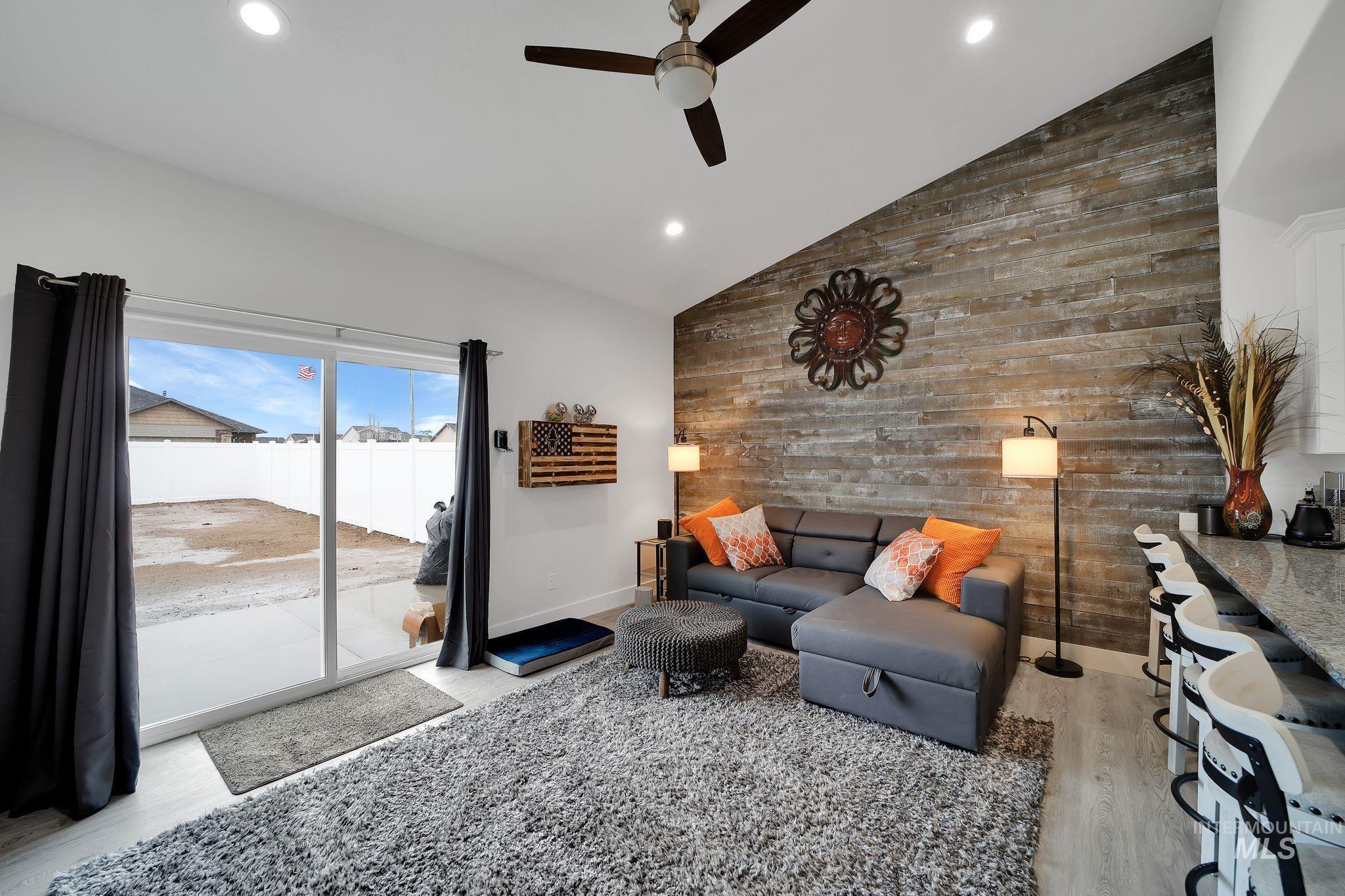Living room featuring wood walls, light wood-style floors, recessed lighting, an accent wall, and lofted ceiling