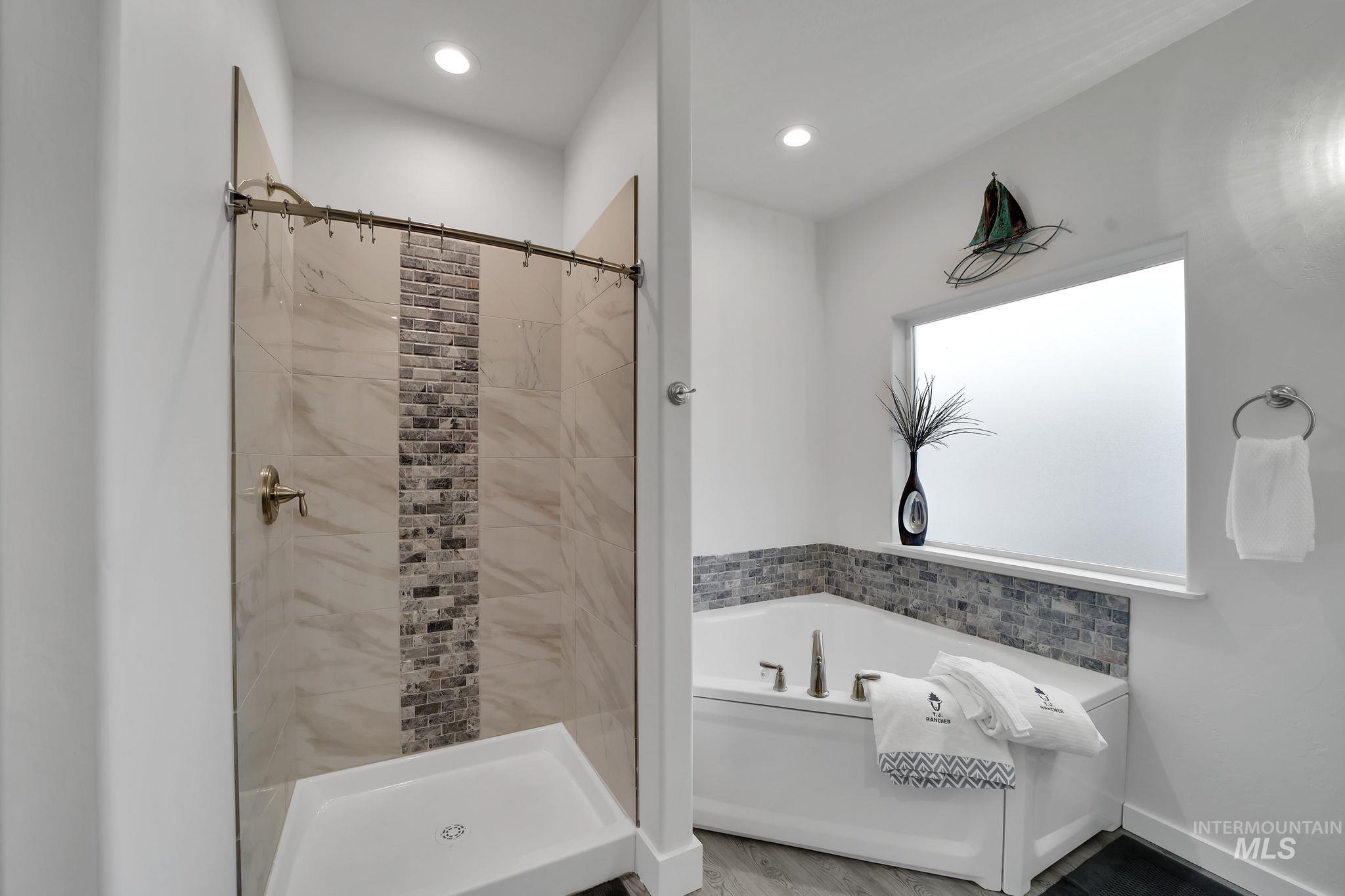 Bathroom with a garden tub, a stall shower, recessed lighting, and wood finished floors