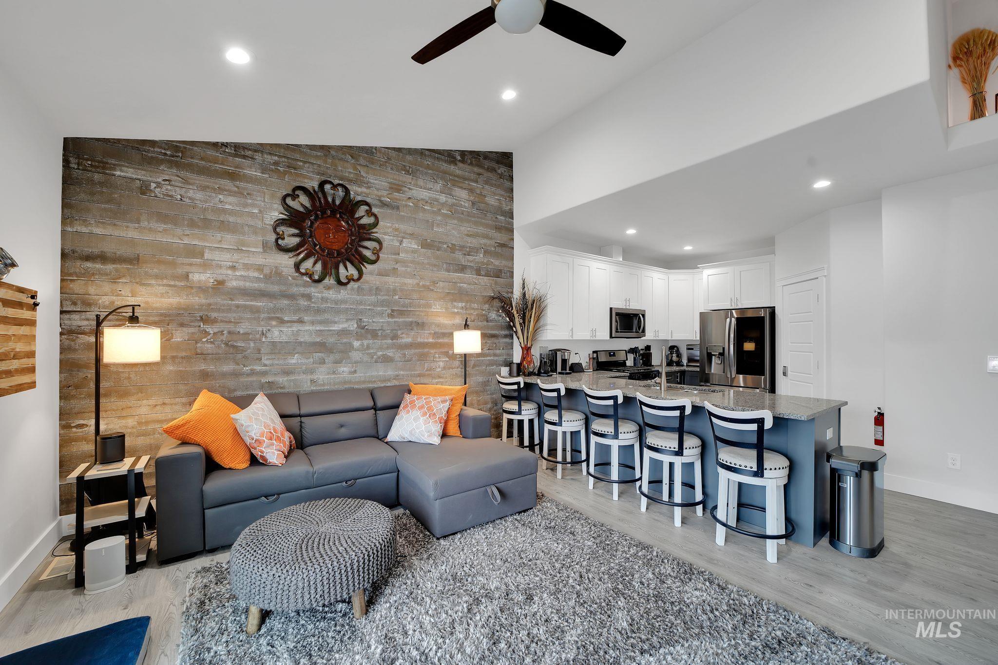 Living area featuring an accent wall, wooden walls, recessed lighting, ceiling fan, and light wood-style floors