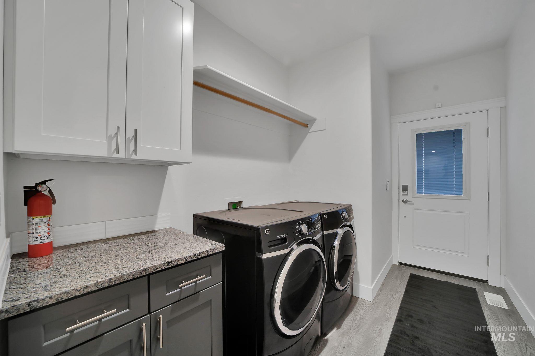 Laundry area with light wood-style flooring, independent washer and dryer, and cabinet space