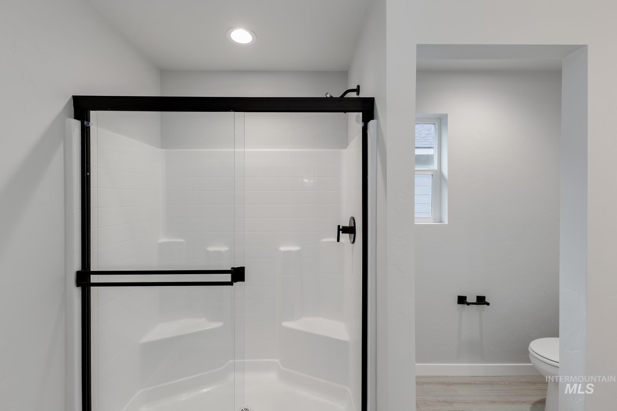 Full bathroom featuring a stall shower and light wood-style floors
