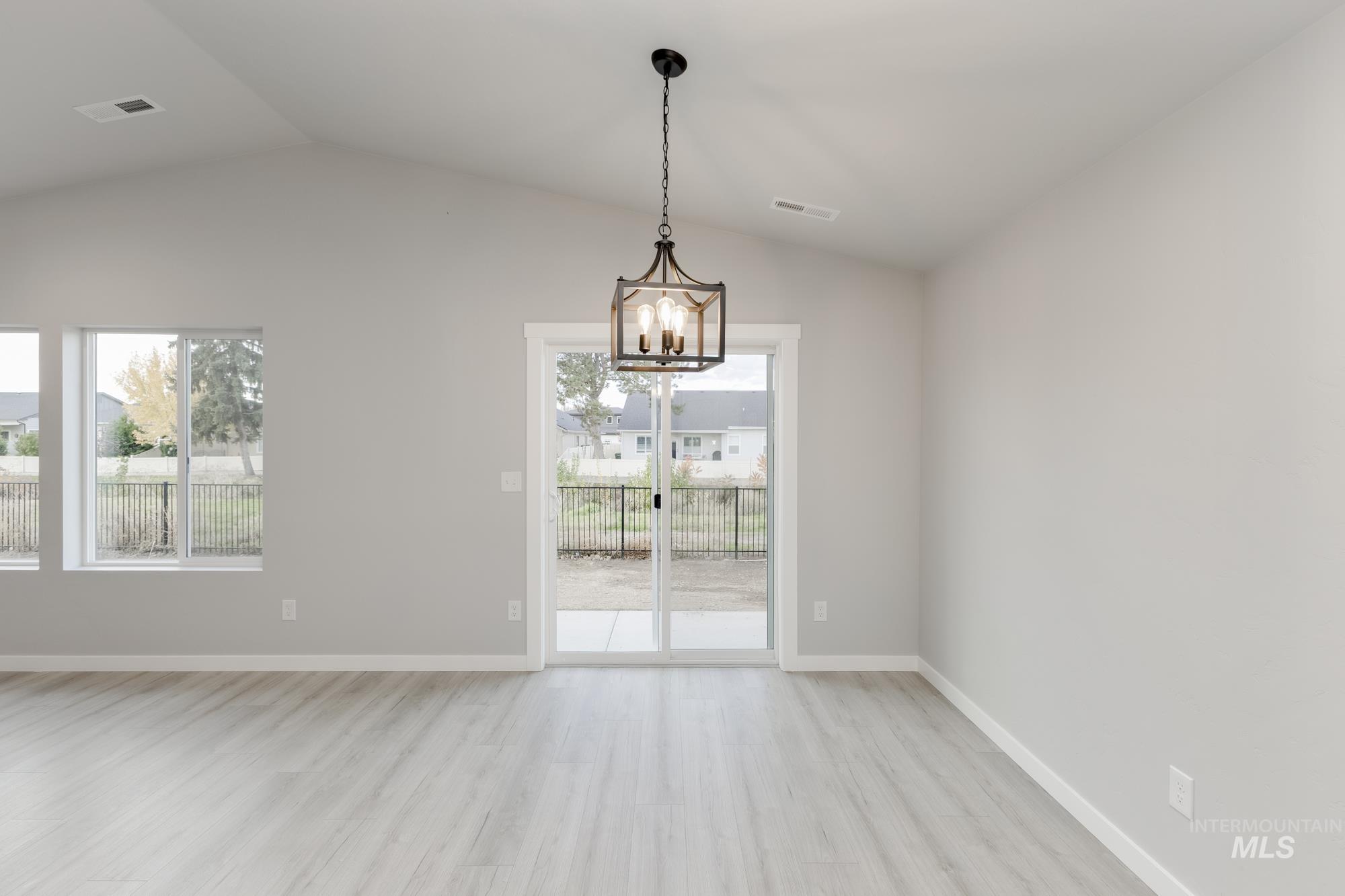 Unfurnished dining area with light wood-style flooring, lofted ceiling, and a chandelier