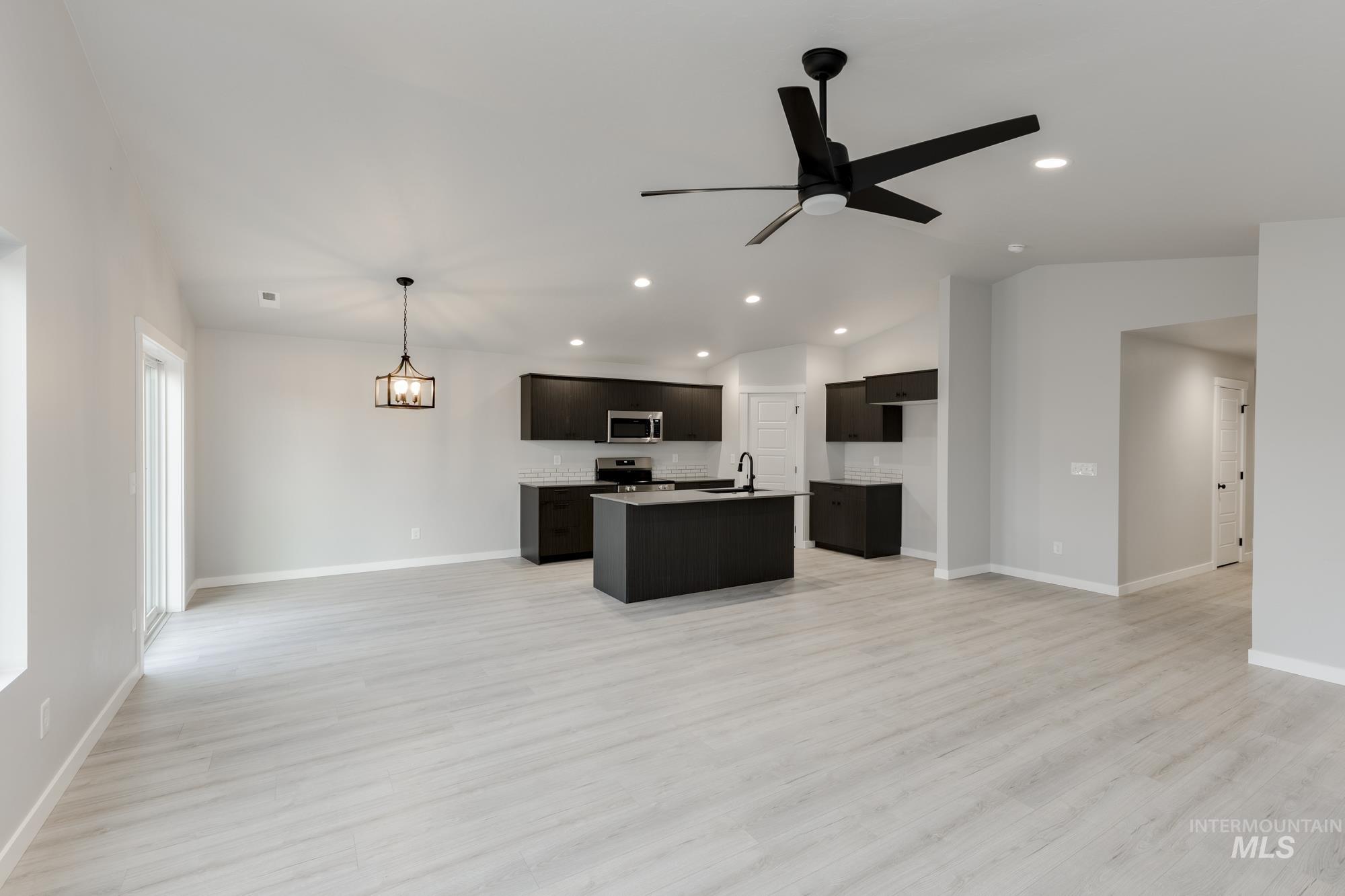 Kitchen with open floor plan, vaulted ceiling, recessed lighting, and light wood finished floors