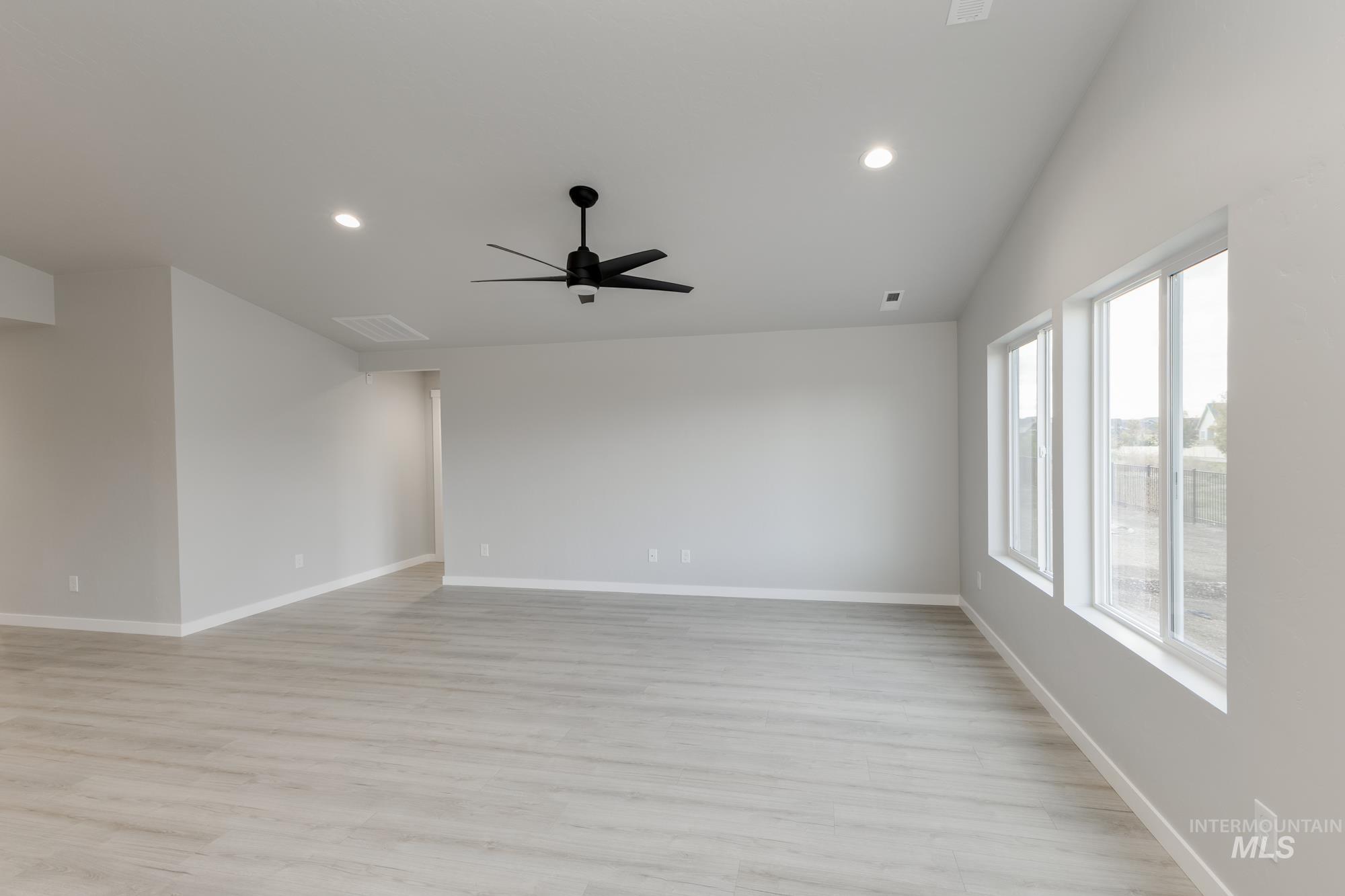Empty room with light wood finished floors, recessed lighting, a ceiling fan, and lofted ceiling
