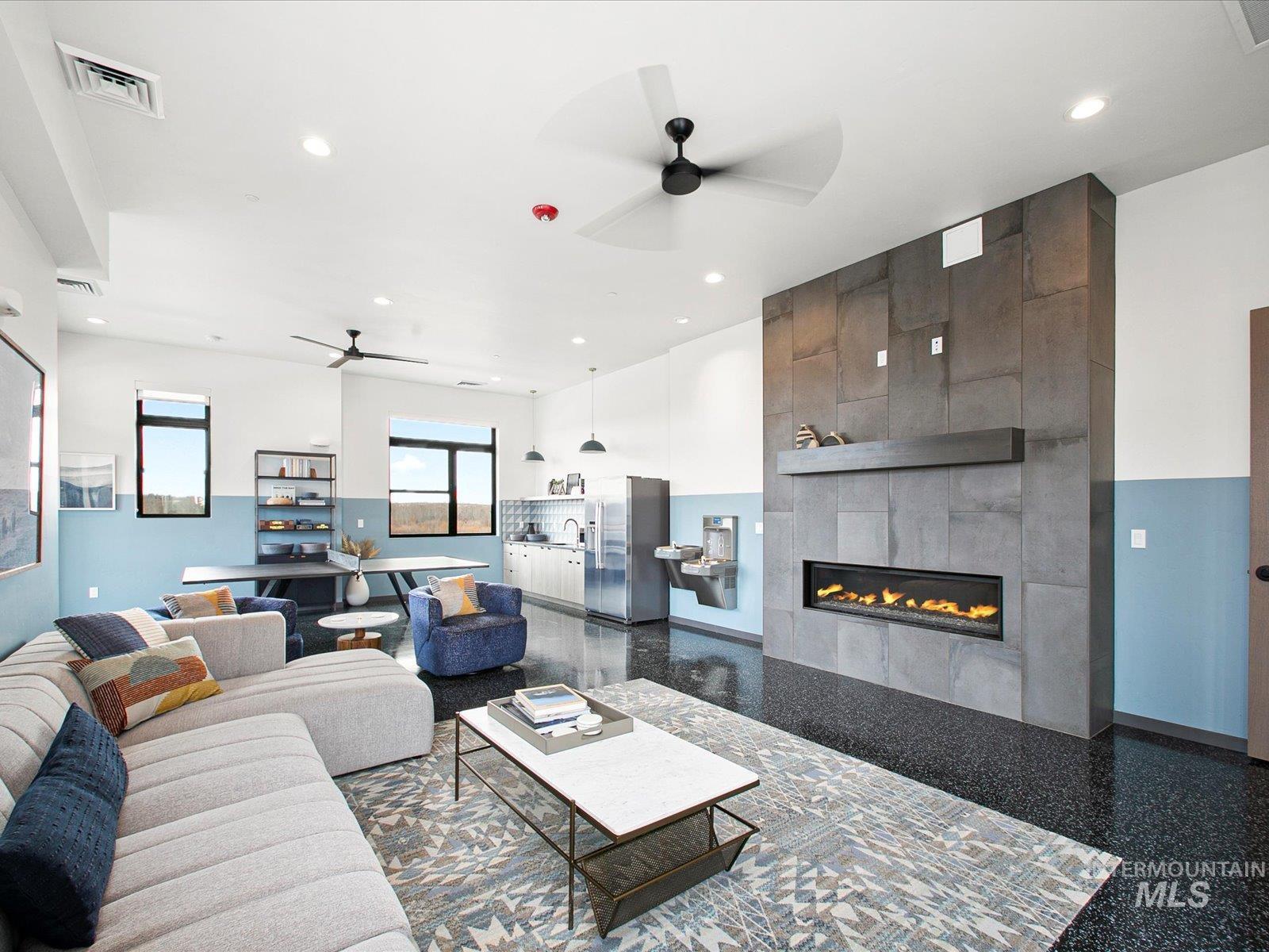 Living room featuring ceiling fan, a tiled fireplace, recessed lighting, and granite floors