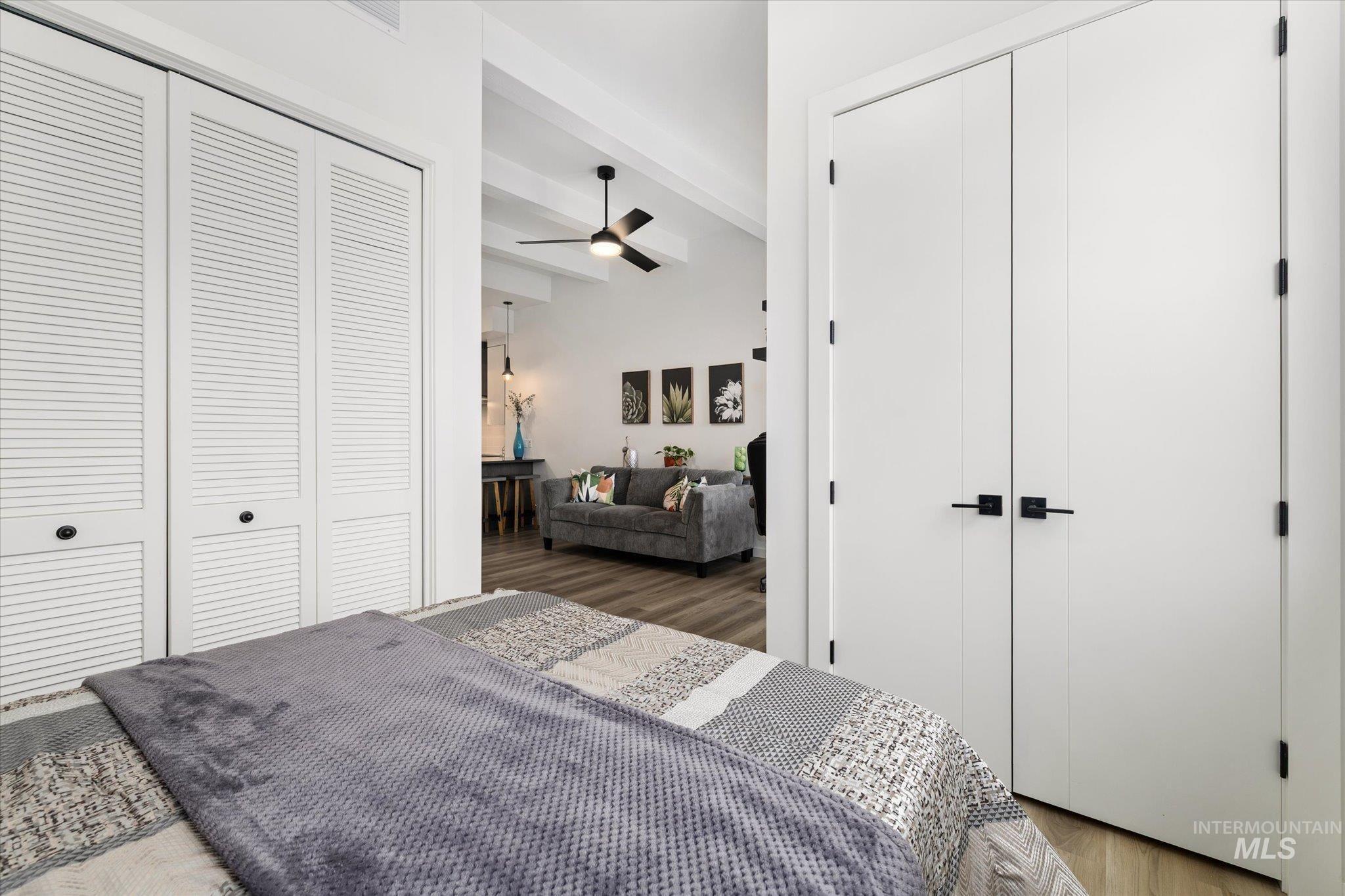 Bedroom with a closet, wood finished floors, and beamed ceiling