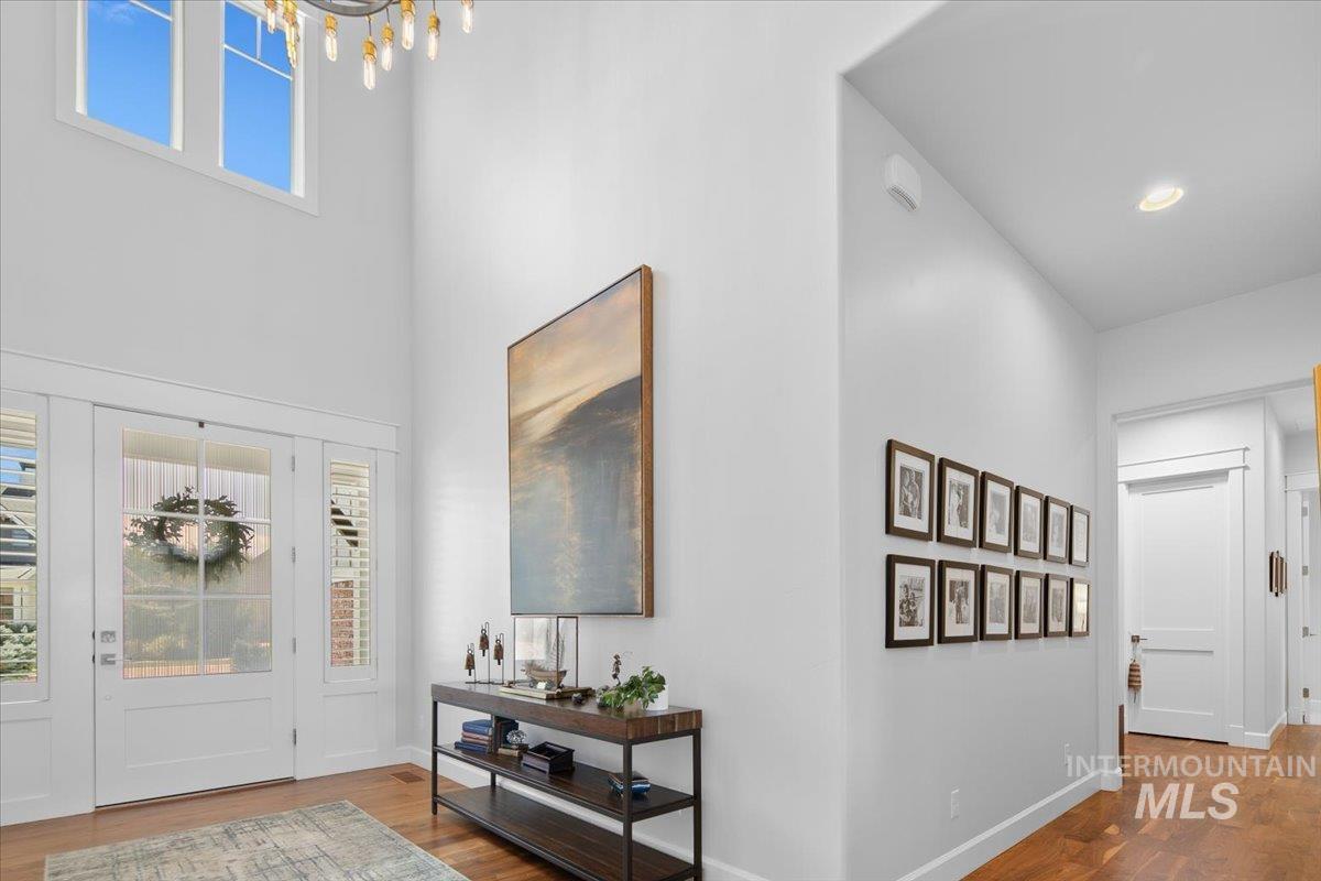 Foyer with wood finished floors, a chandelier, and a high ceiling