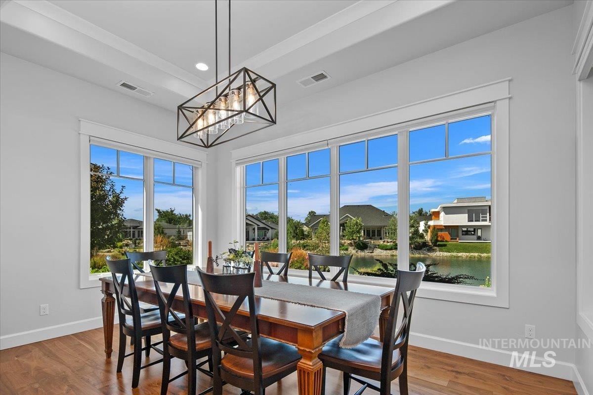 Dining space with a chandelier, wood finished floors, a water view, and recessed lighting