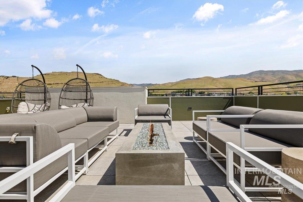 View of patio with a mountain view and an outdoor living space with a fire pit