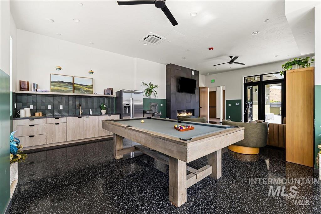 Recreation room with billiards table, ceiling fan, and a large fireplace