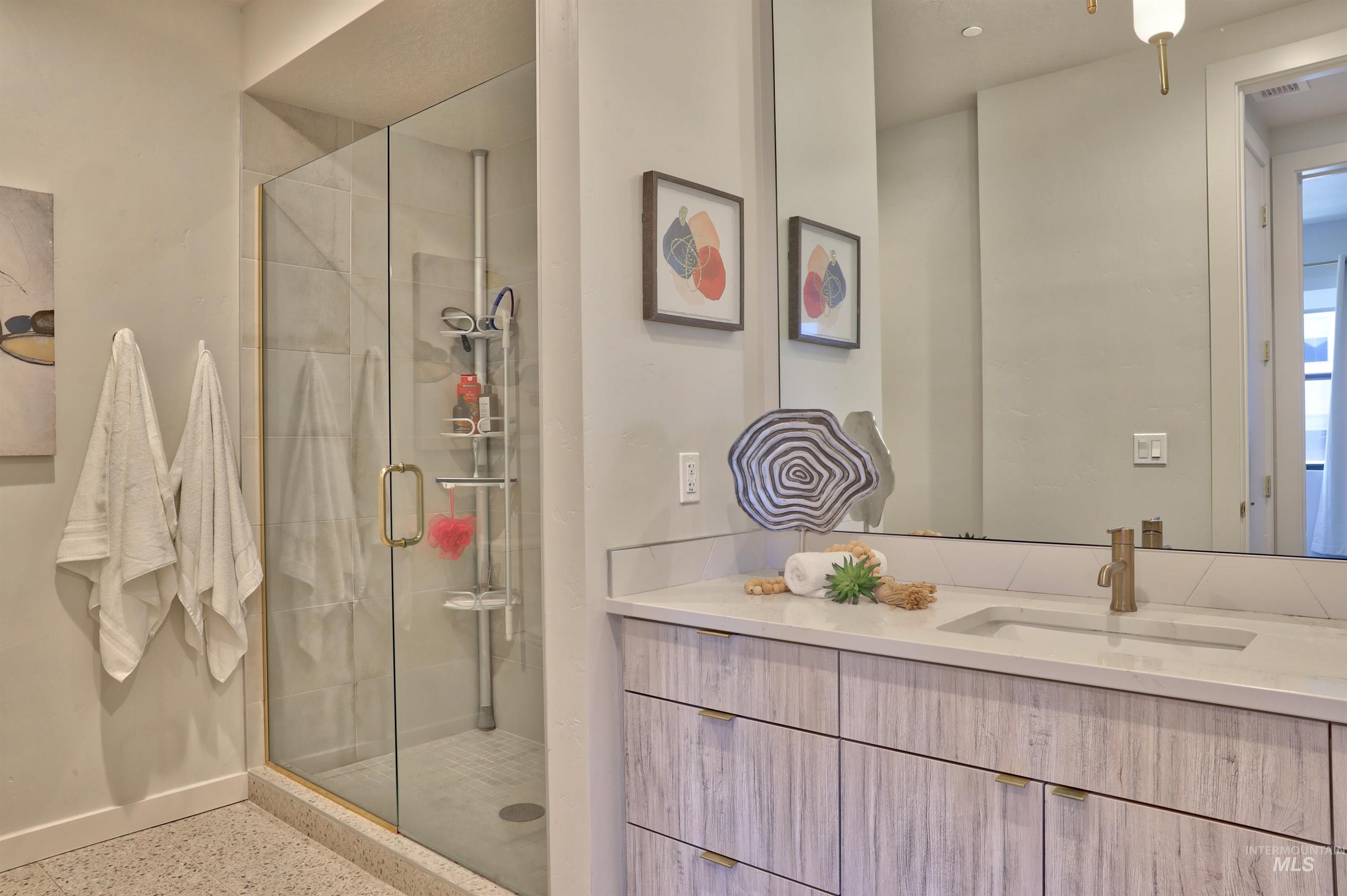Bathroom featuring vanity, a shower stall, and dark speckled floor