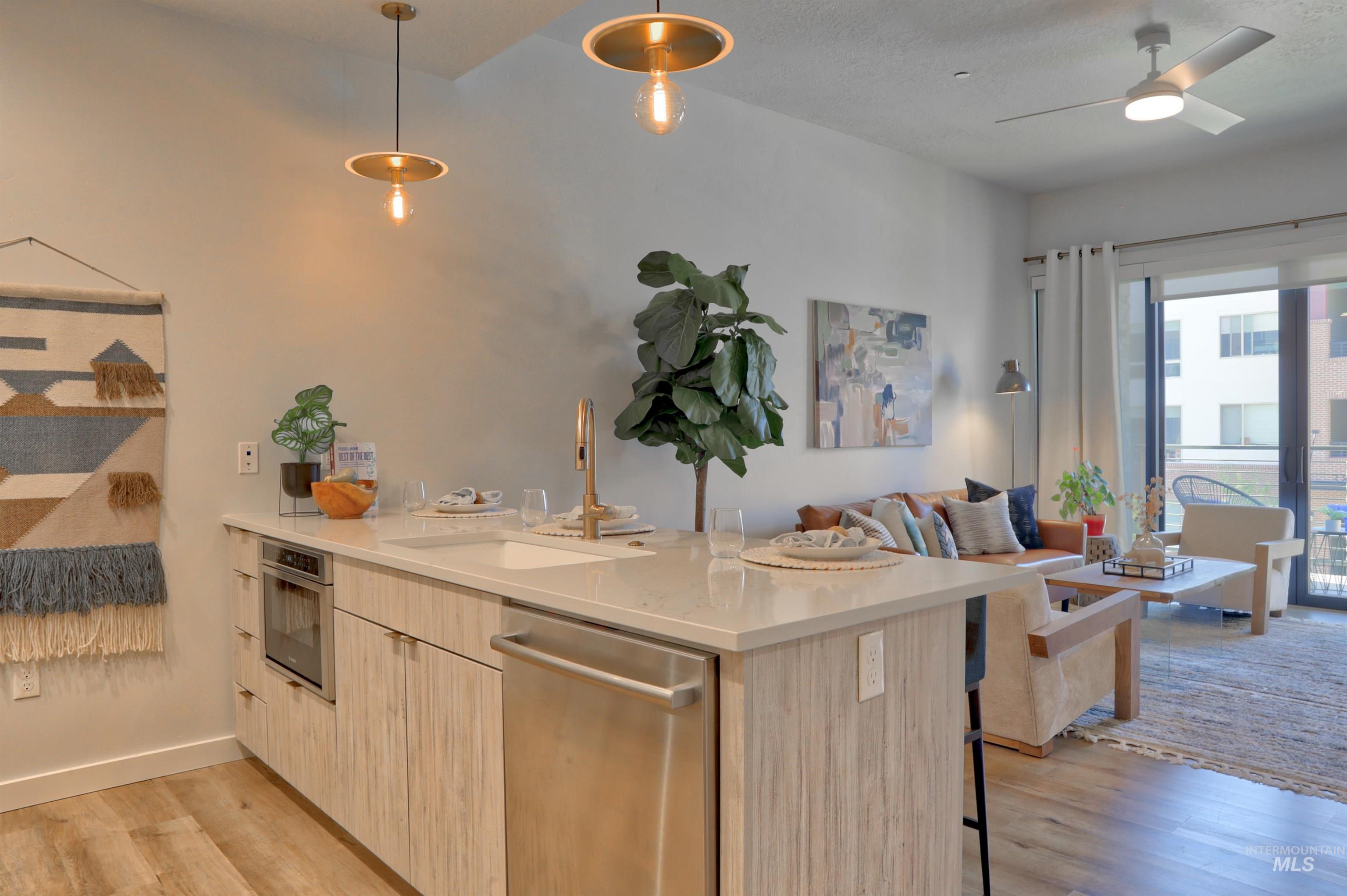 Kitchen with light brown cabinets, a peninsula, light wood-type flooring, modern cabinets, and appliances with stainless steel finishes