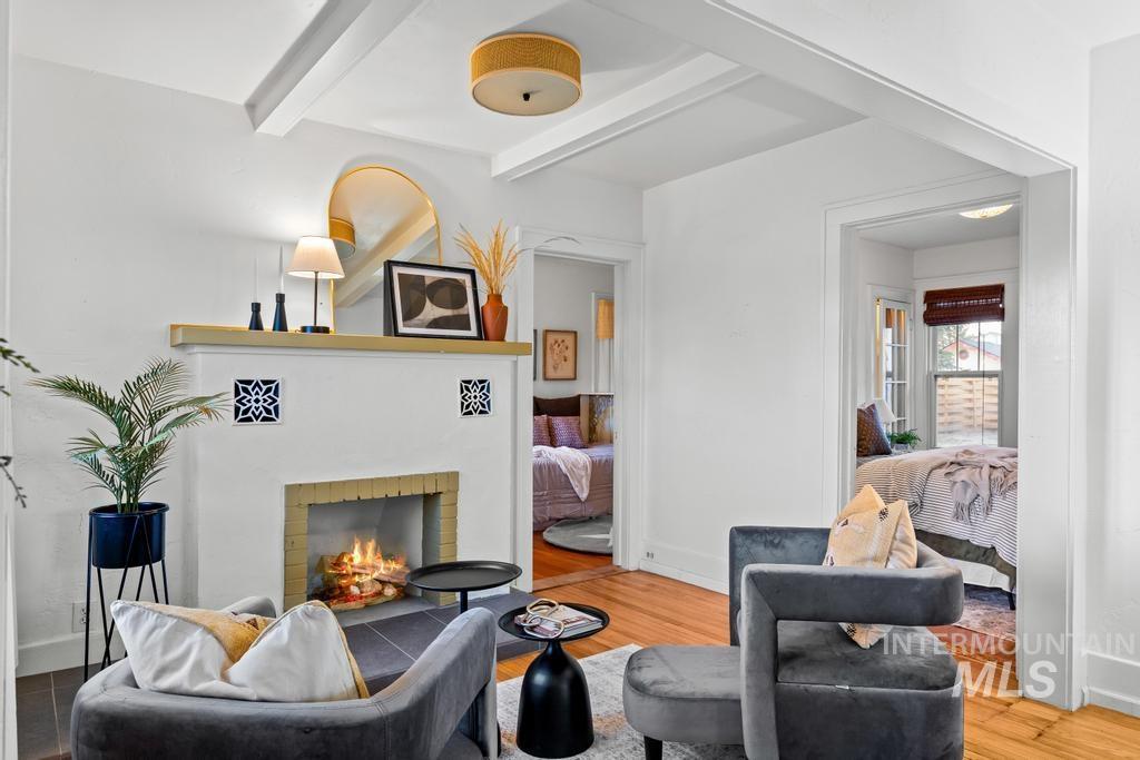 Living area featuring beamed ceiling, a brick fireplace, and wood finished floors