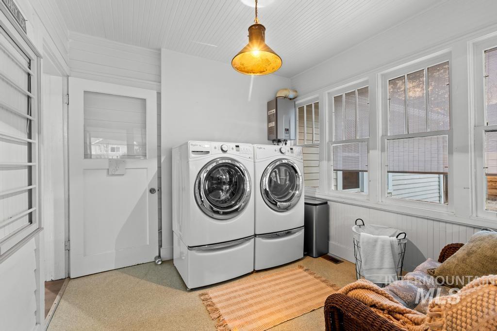 Laundry area with wooden walls, water heater, and separate washer and dryer