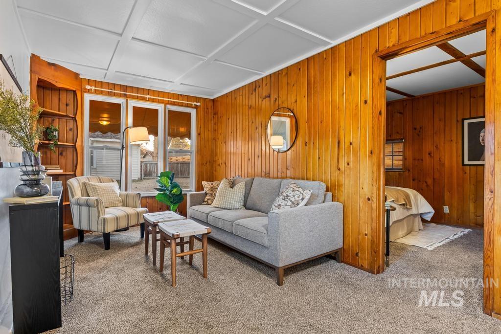Carpeted living room featuring wooden walls