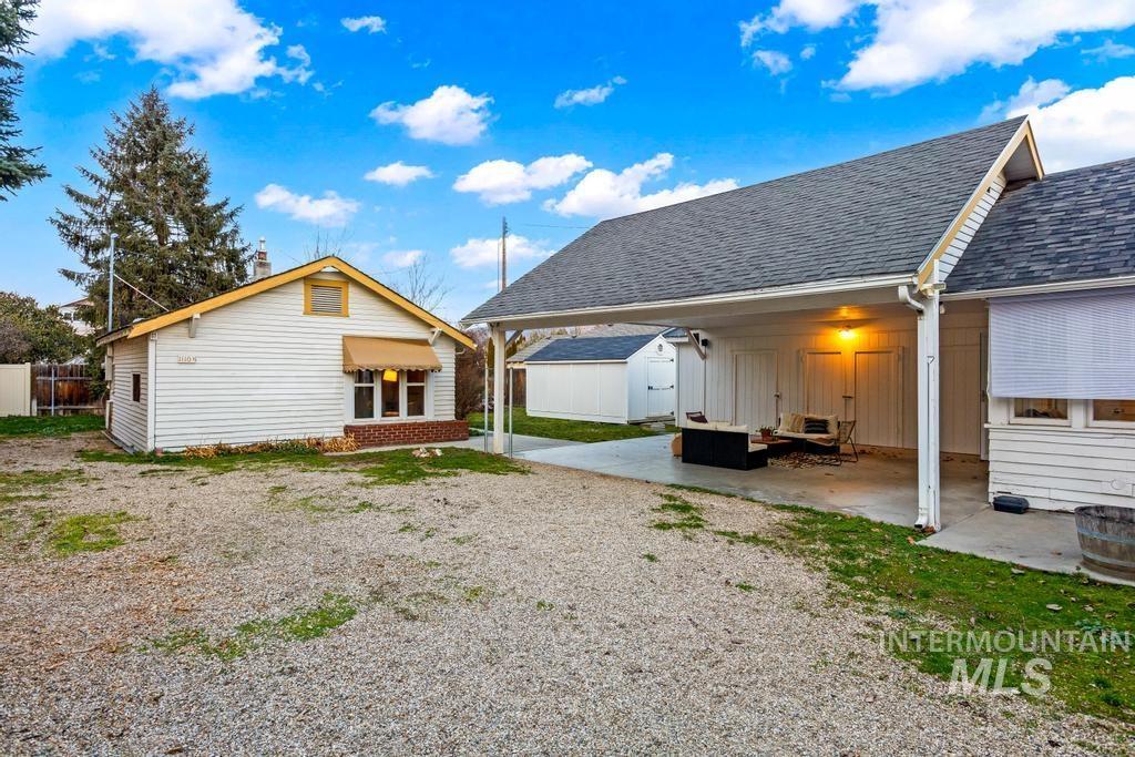 Back of property with roof with shingles, an outdoor structure, a patio area, and board and batten siding