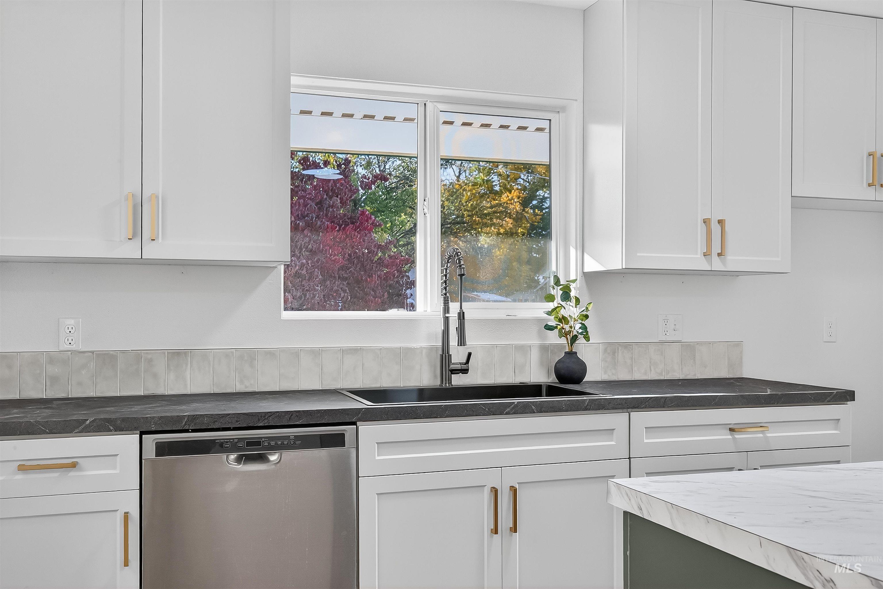 Kitchen featuring white cabinets, dishwasher, and dark countertops