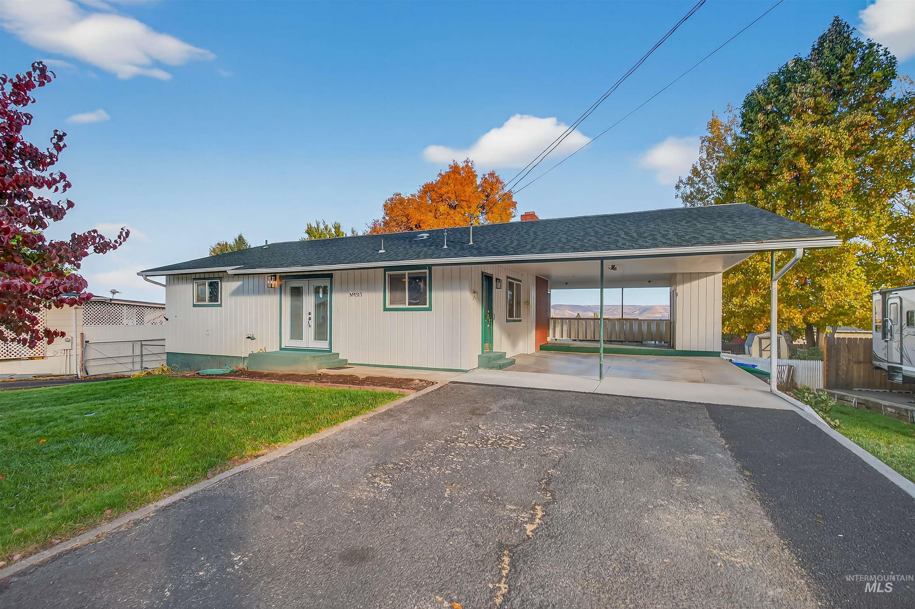 Ranch-style house featuring a shingled roof, asphalt driveway, and an attached carport