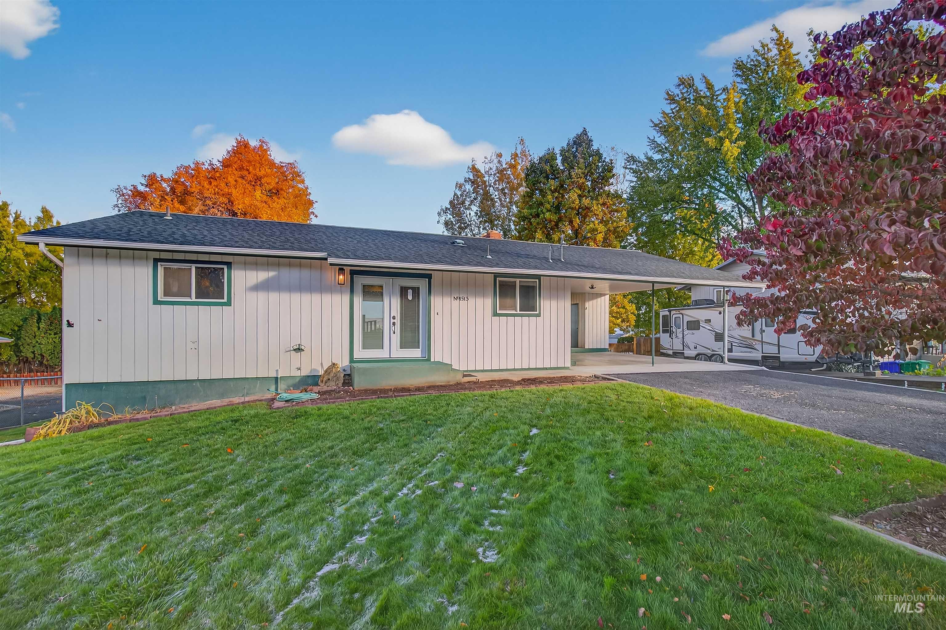 Single story home featuring a front lawn, a shingled roof, a carport, asphalt driveway, and french doors