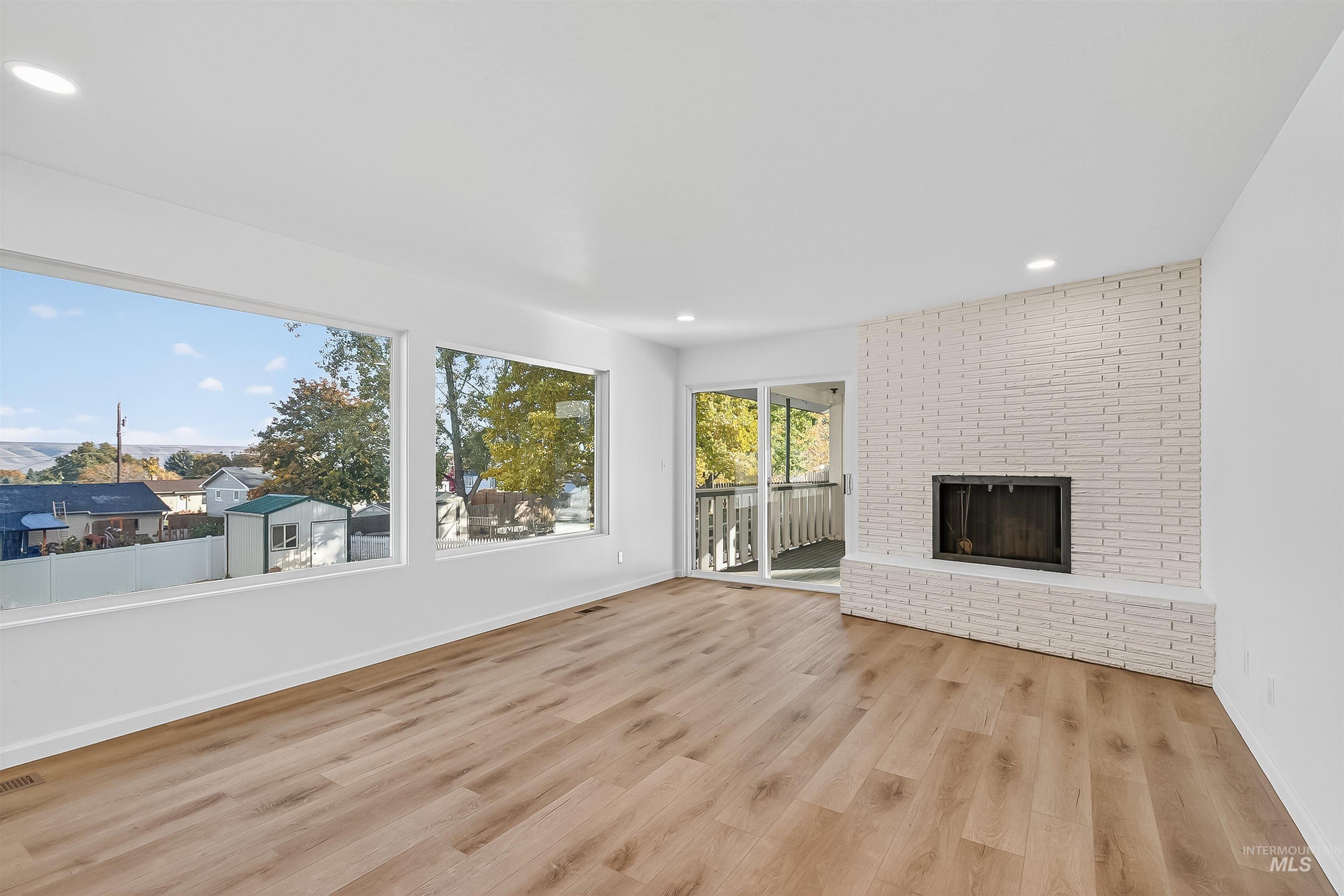 Unfurnished living room with a fireplace, light wood-type flooring, and recessed lighting