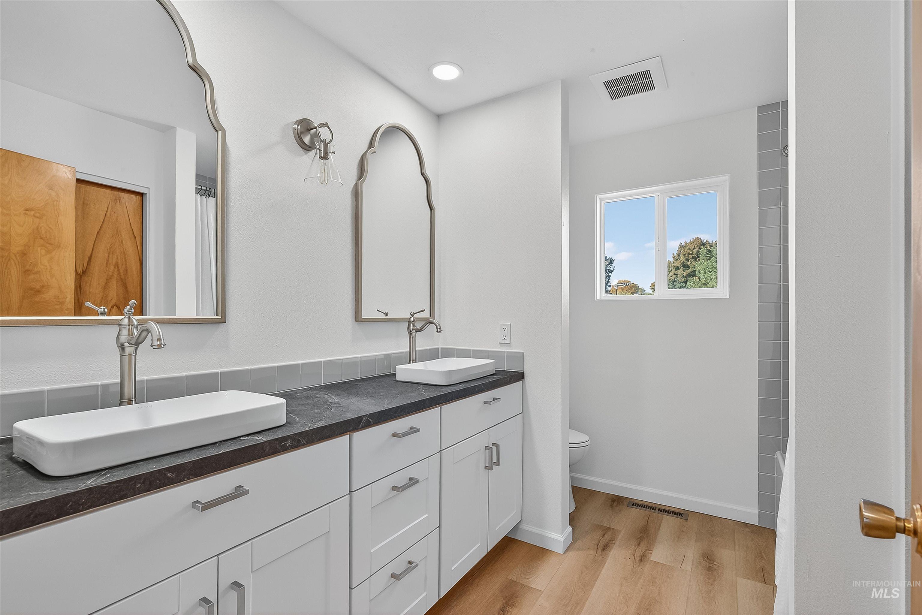 Full bathroom with double vanity, light wood finished floors, a shower with curtain, and recessed lighting