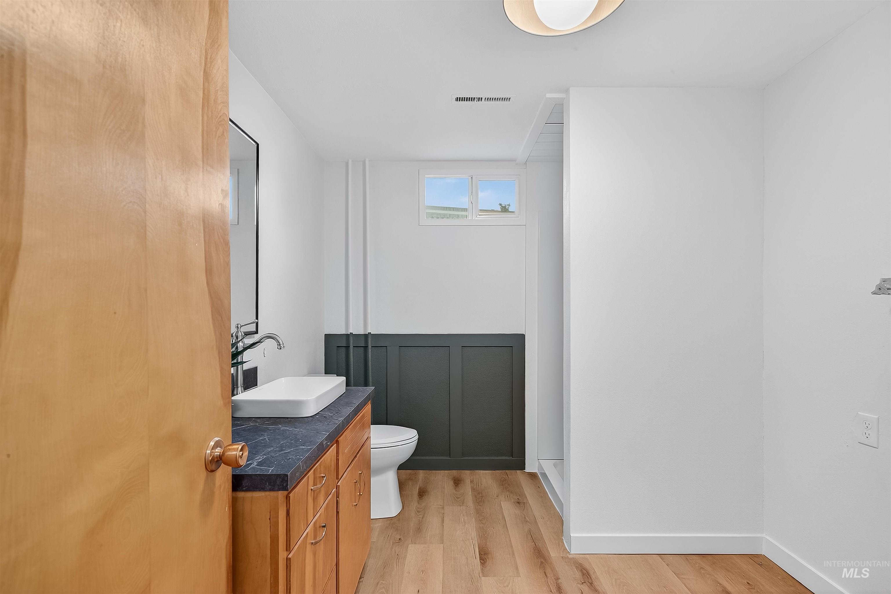 Full bath with light wood-type flooring and vanity