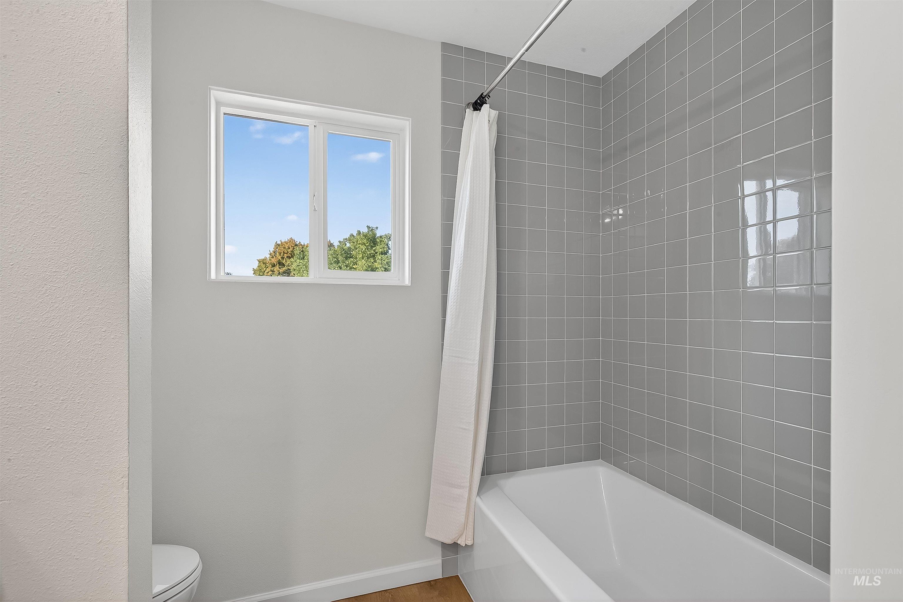Full bathroom with shower / bath combination with curtain and baseboards