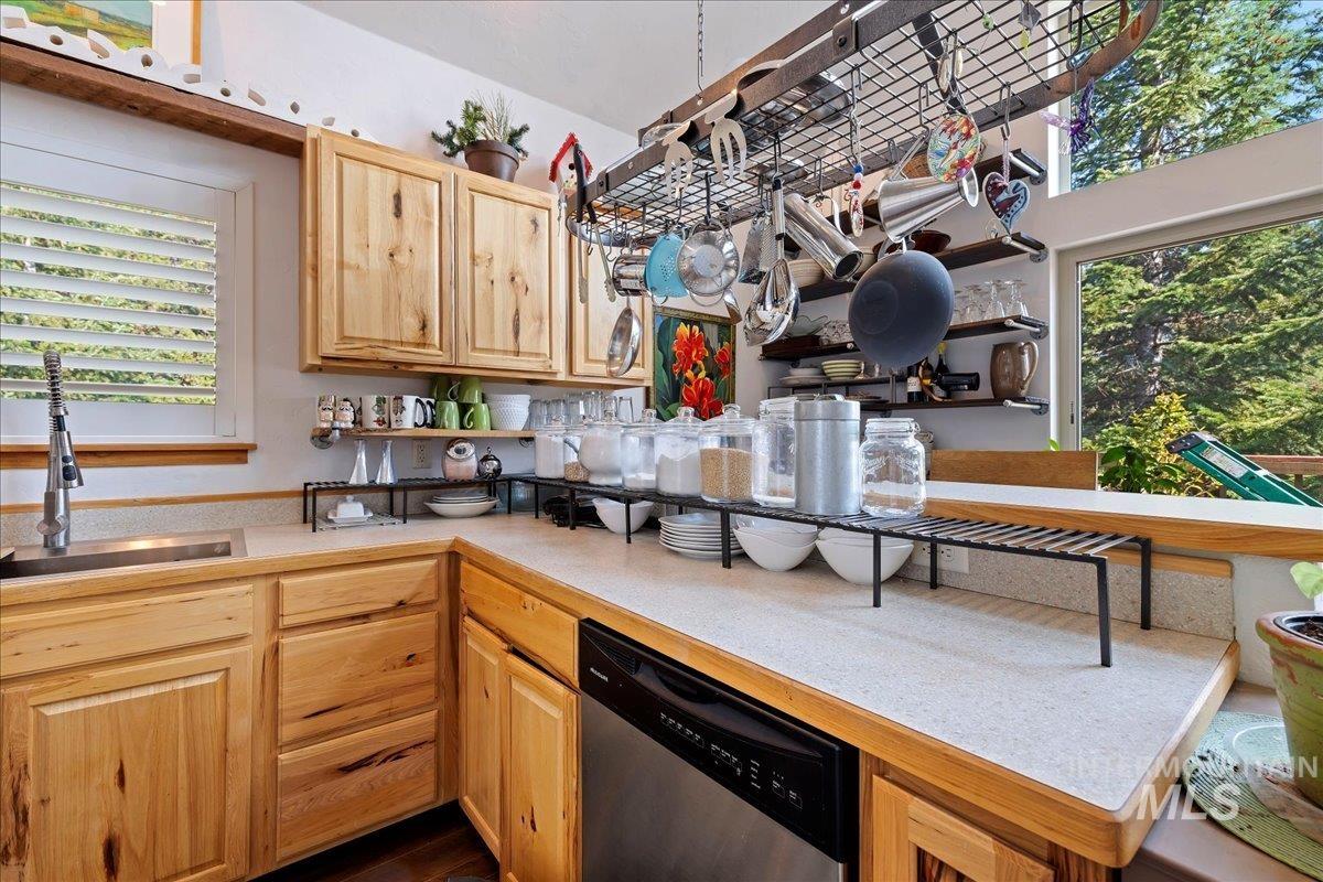 Kitchen featuring open shelves, plenty of natural light, light countertops, and dishwasher