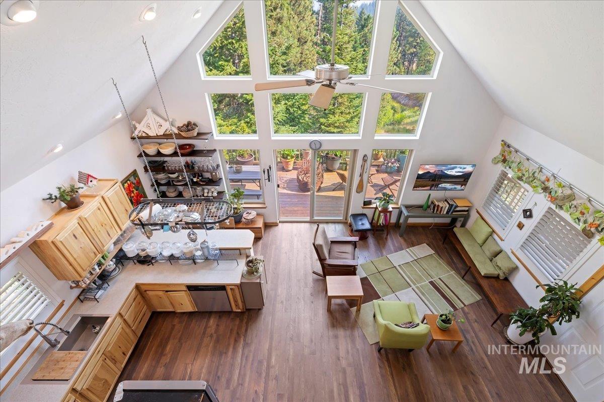 Living room featuring high vaulted ceiling, plenty of natural light, dark wood-style flooring, and a ceiling fan