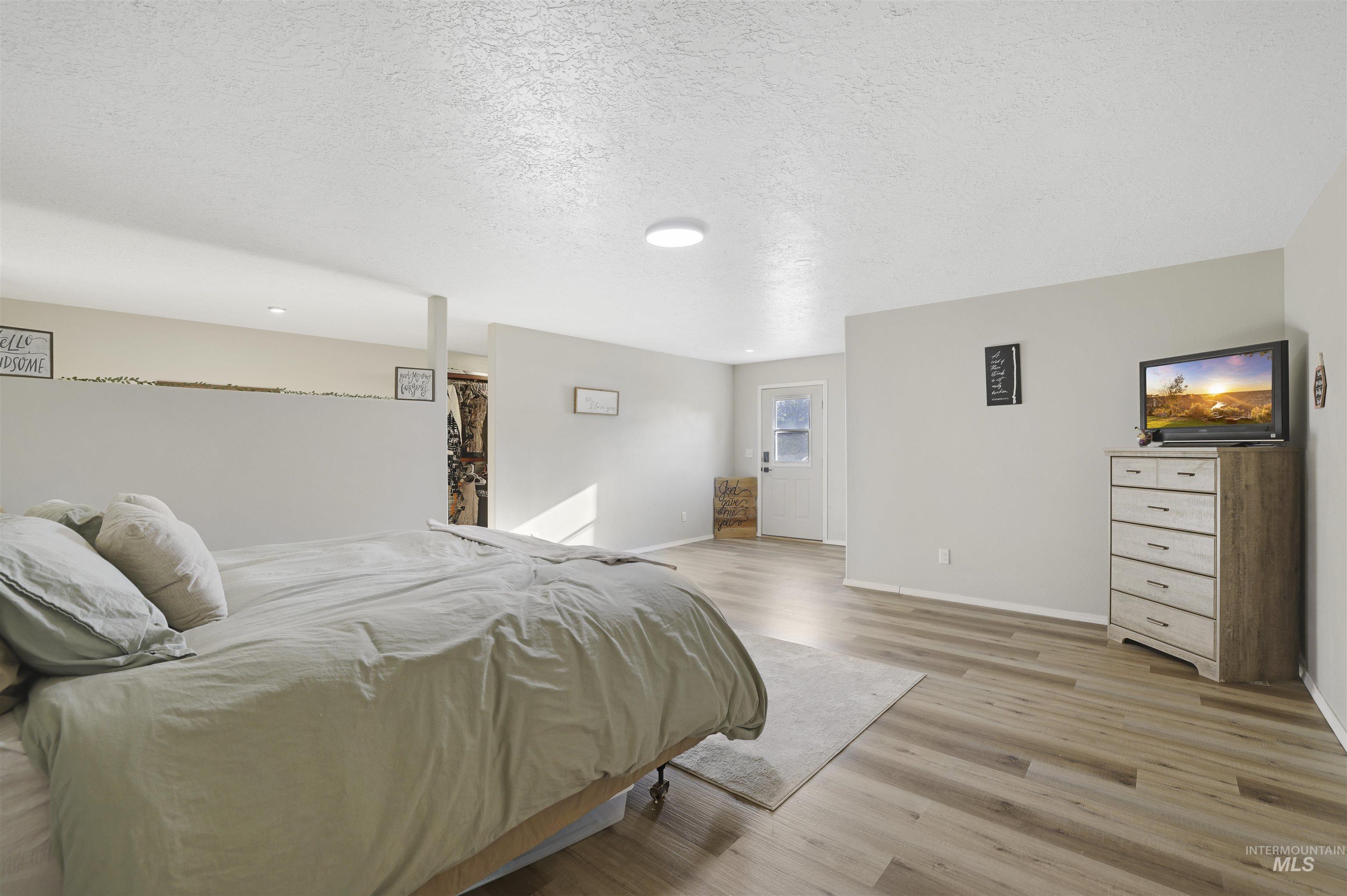 Bedroom with a textured ceiling and light wood-style flooring