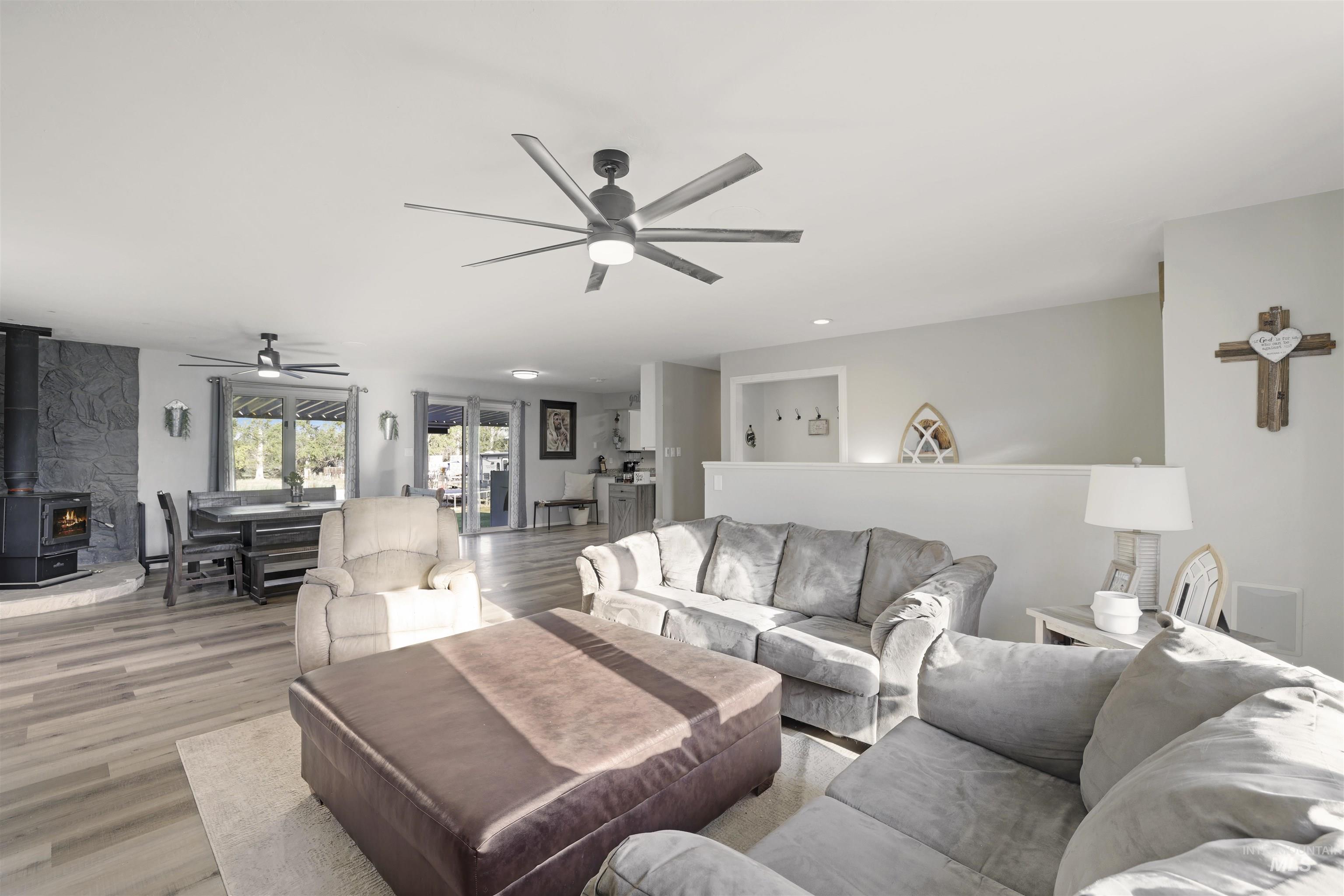 Living area with a wood stove, wood finished floors, a ceiling fan, and recessed lighting