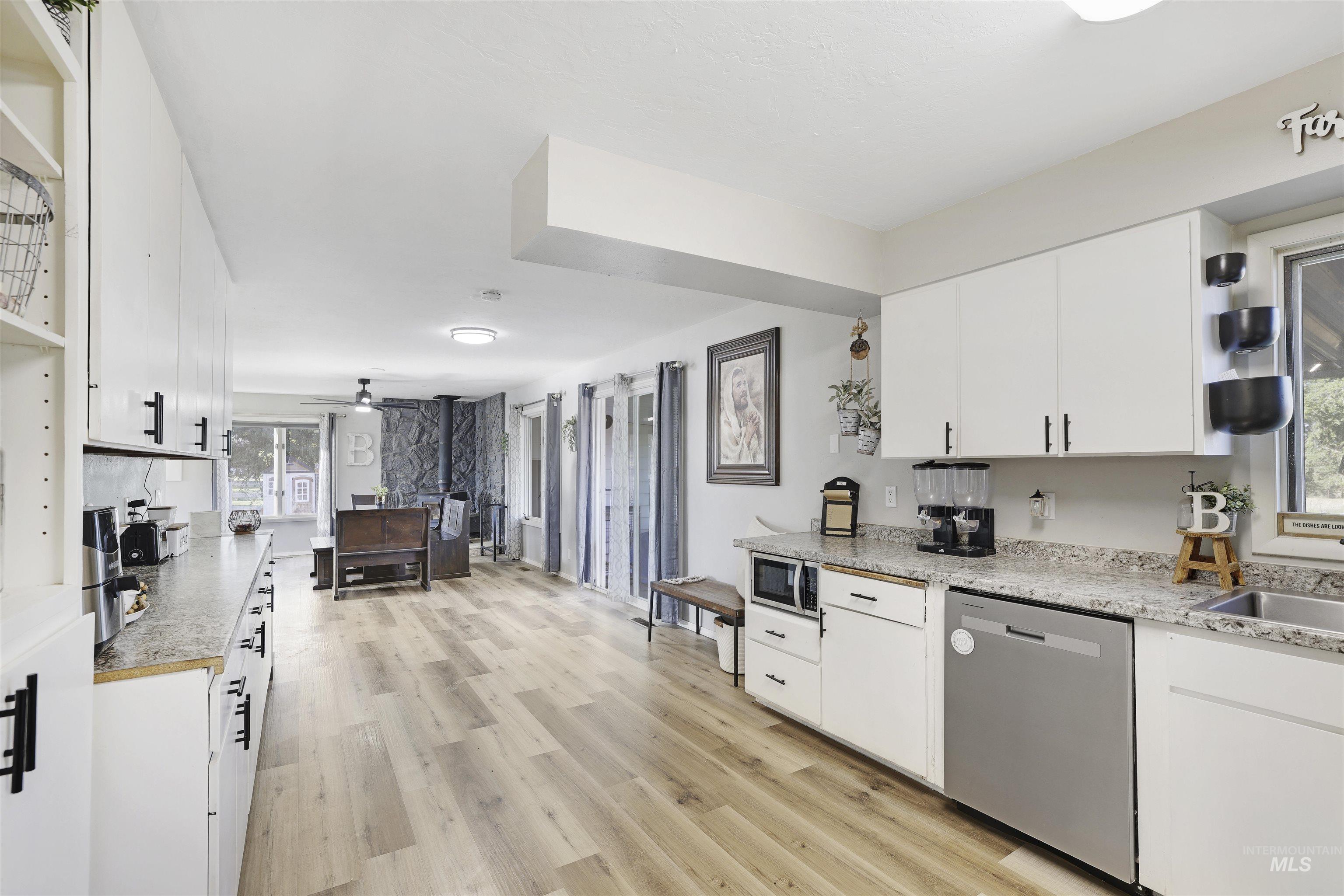 Kitchen featuring white cabinets, open shelves, light countertops, and stainless steel appliances