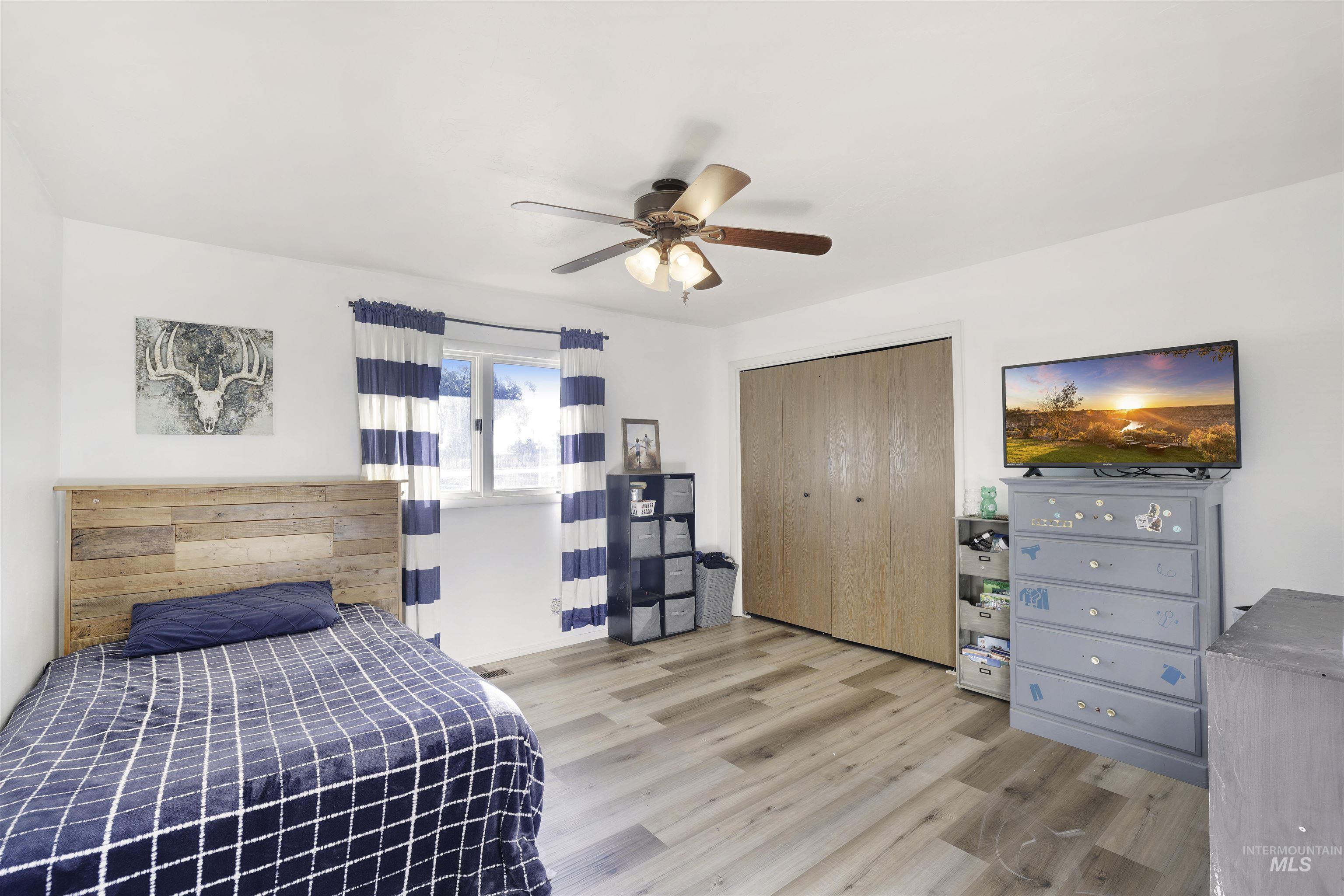 Bedroom with a closet, light wood-style flooring, and a ceiling fan