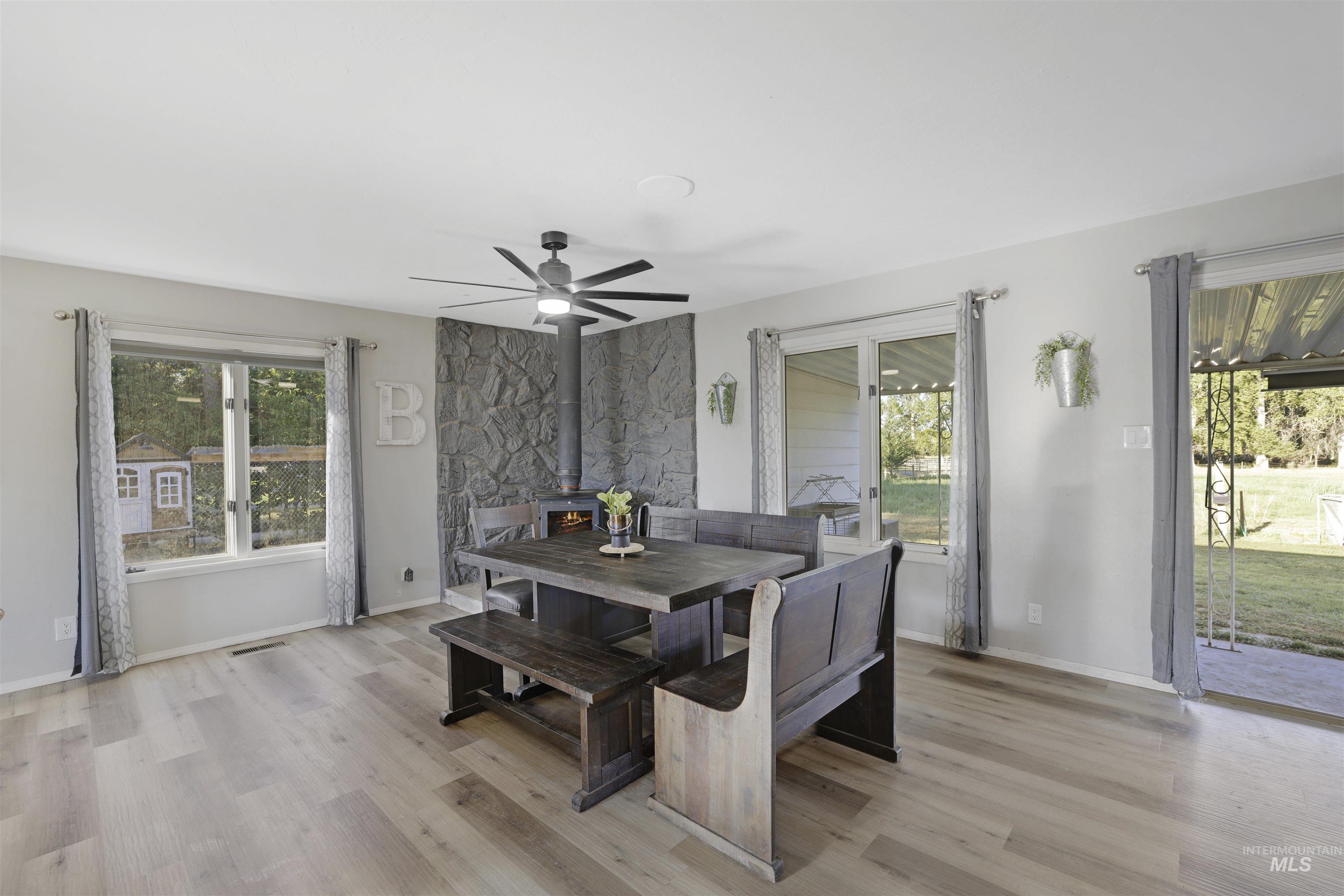 Dining space with a wood stove, light wood-style flooring, and a ceiling fan