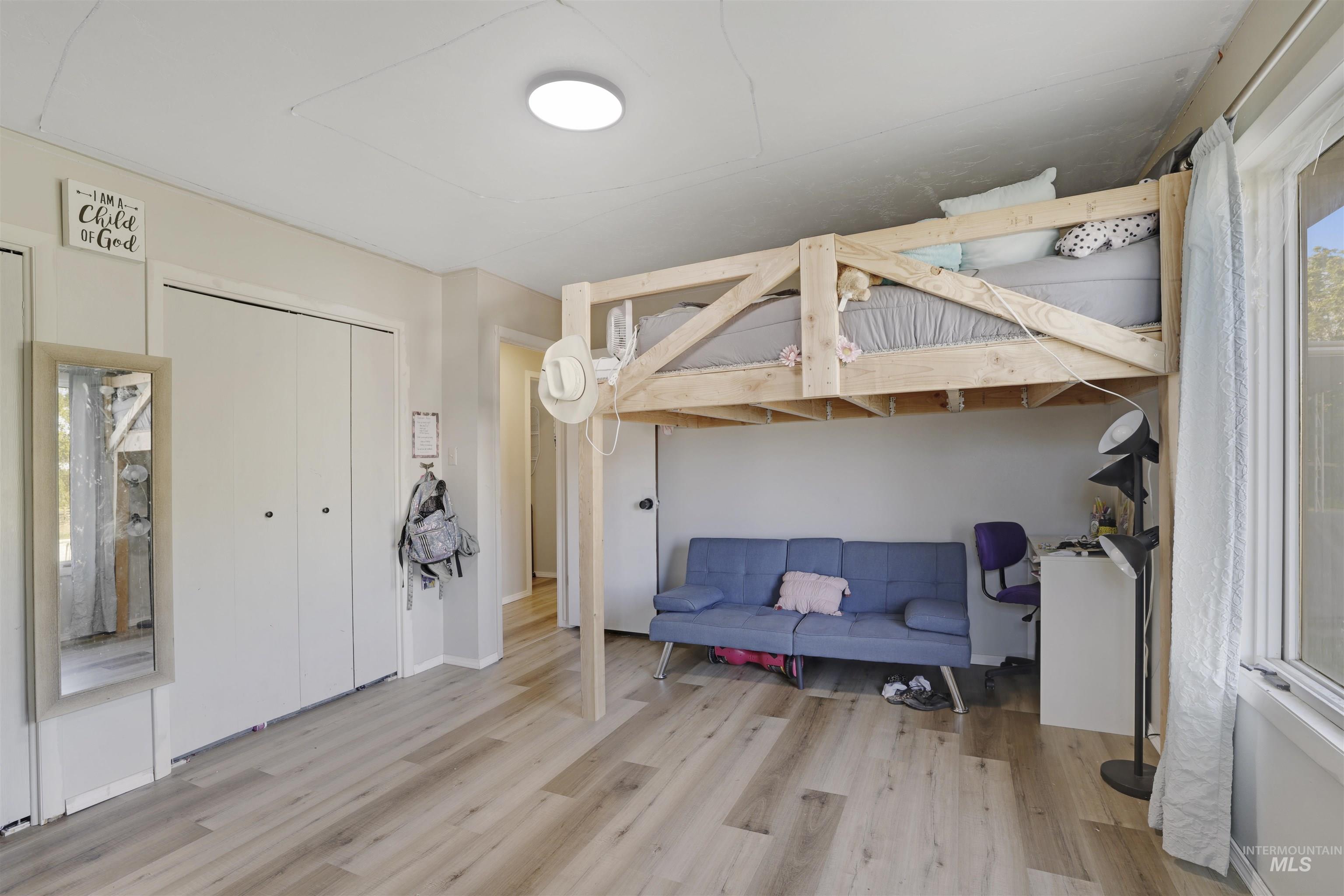 Bedroom with wood finished floors and a closet