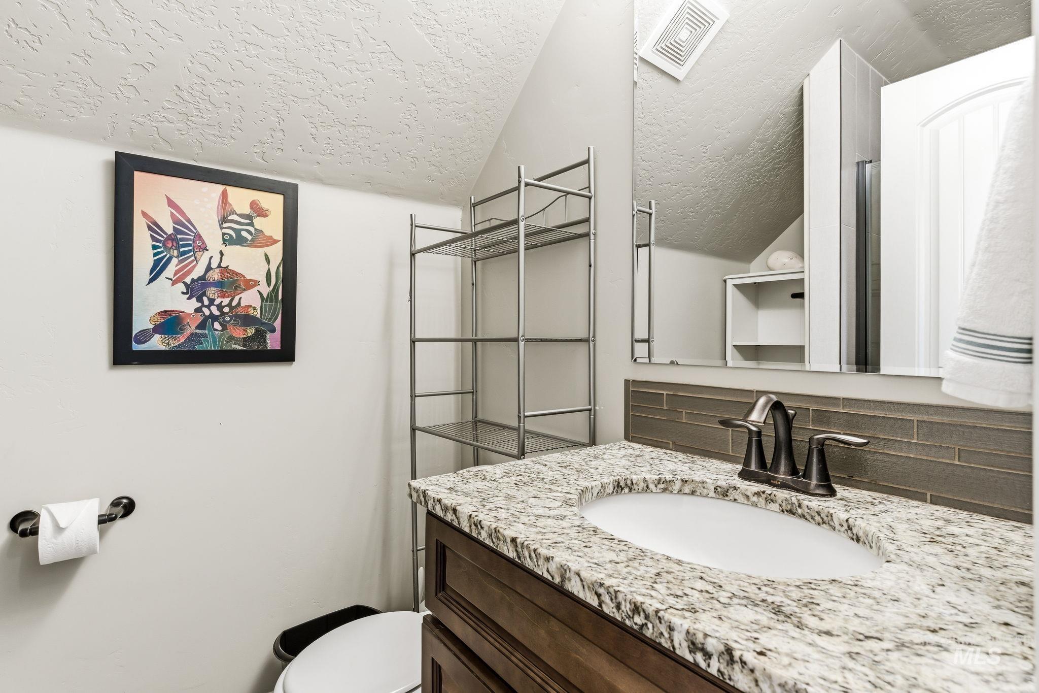 Bathroom vanity featuring a speckled countertop, undermount sink, and dark bronze-finish faucet