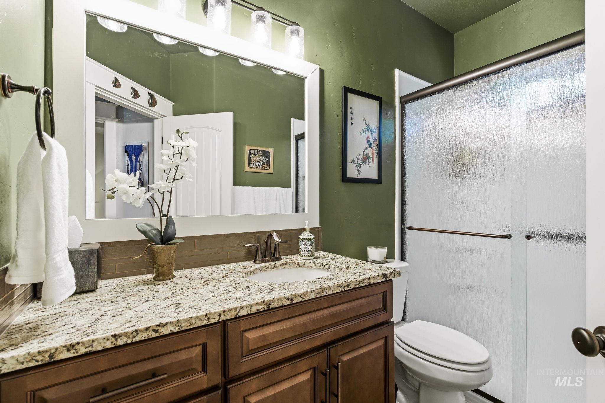 Bathroom featuring a vanity with a granite countertop, undermount sink, and wood-finish cabinetry