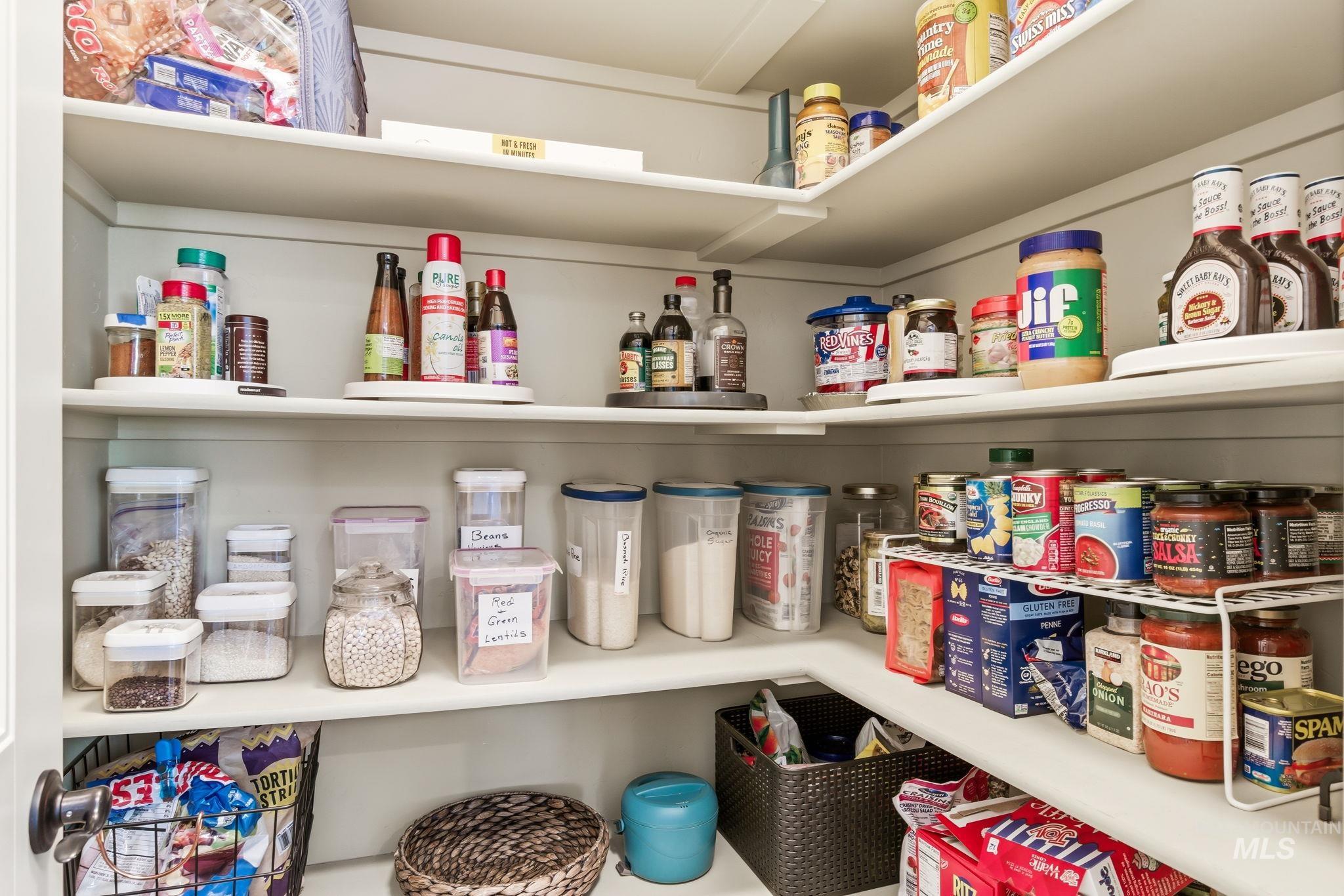 Built-in pantry with multiple white shelves, including corner shelving, providing extensive storage