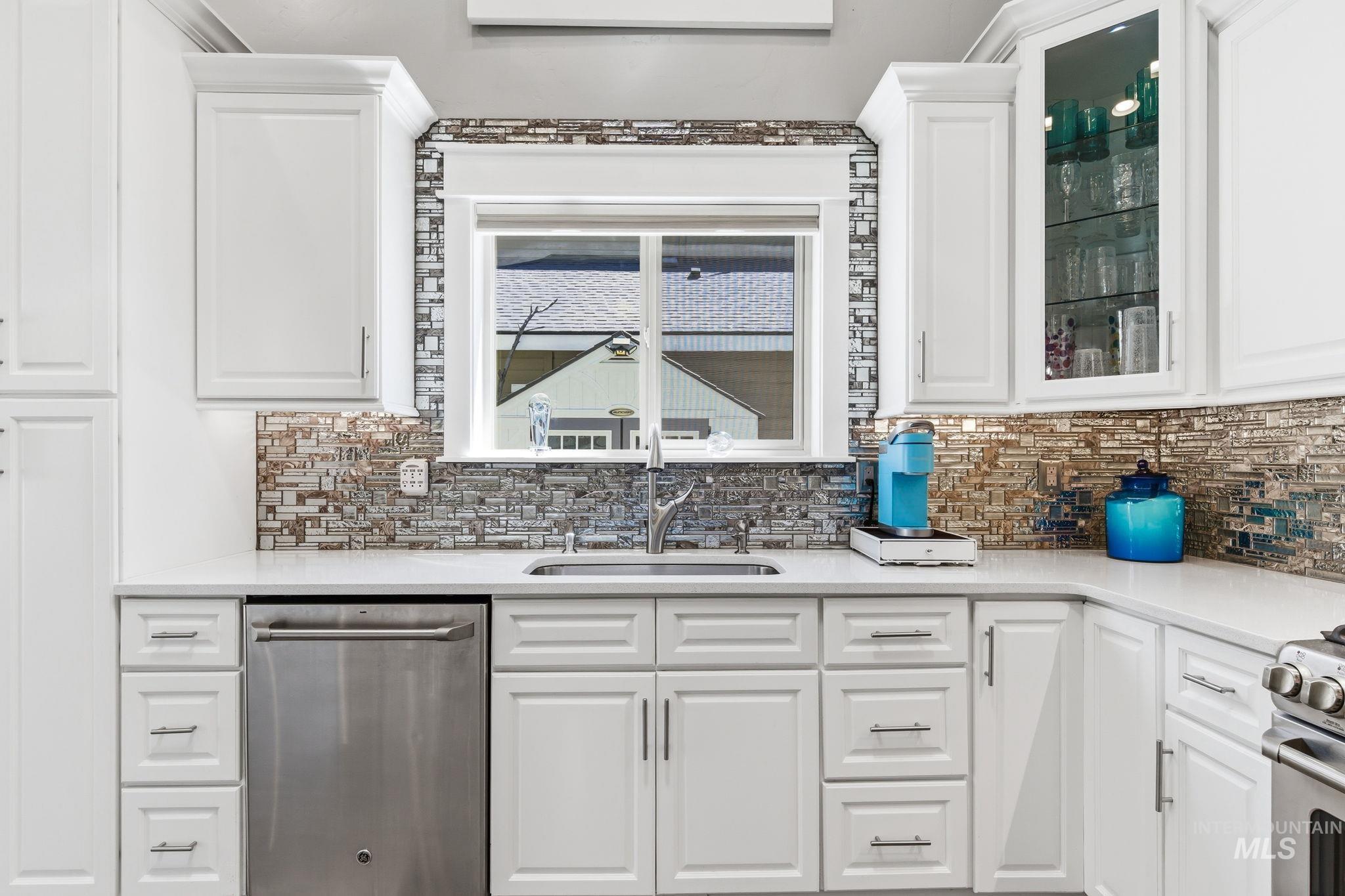 White shaker-style cabinetry with a mosaic tile backsplash and undermount sink