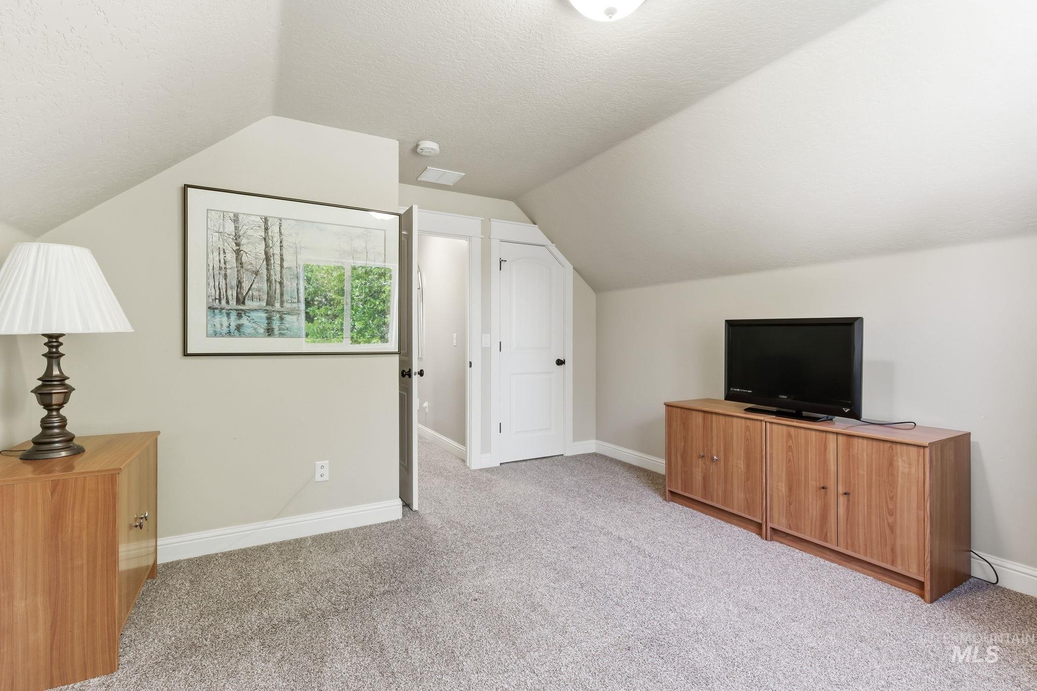 Carpeted room with sloped ceilings and light neutral wall paint